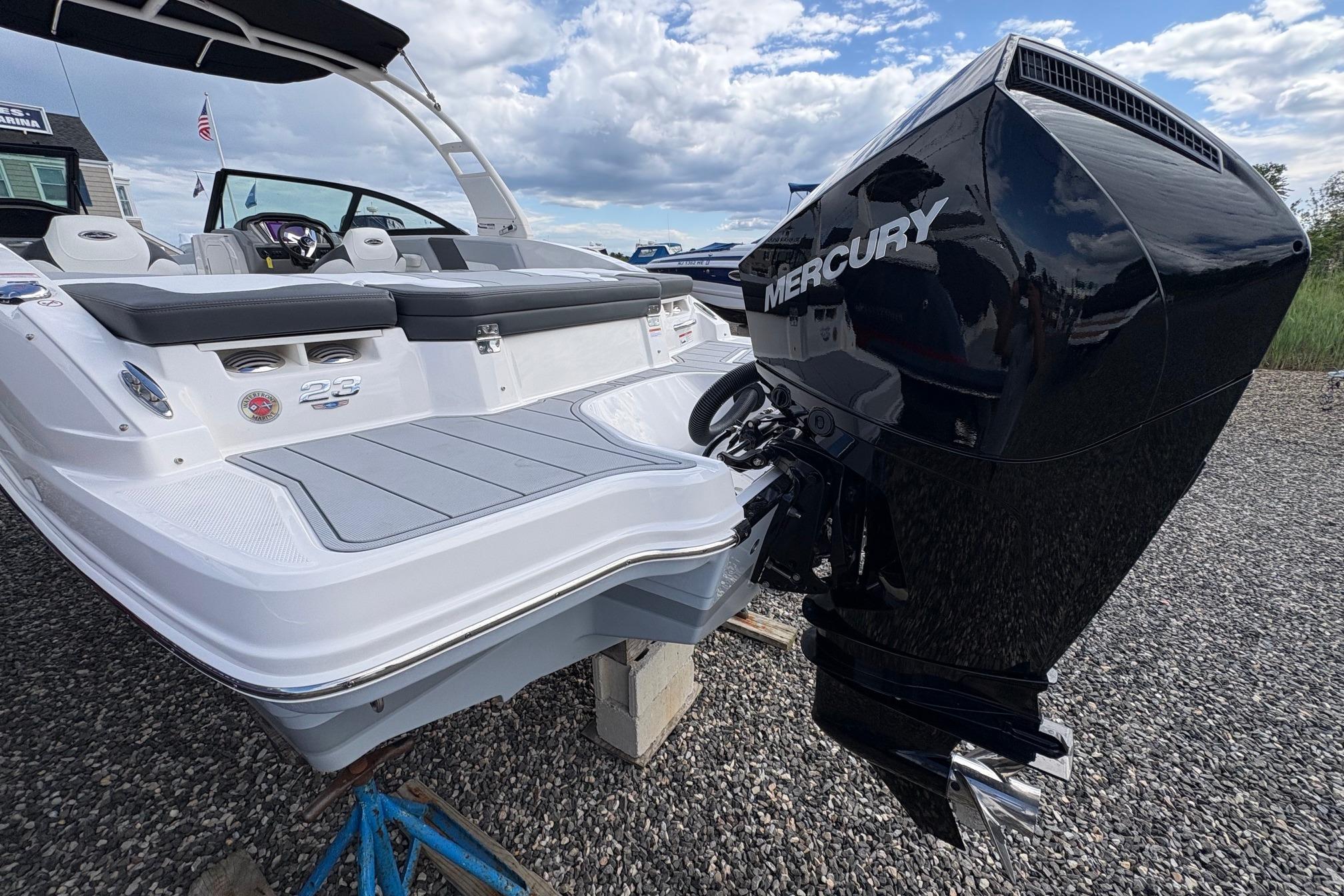 2026 Chaparral 23 SSi OB boat with Mercury outboard engine, docked on gravel.