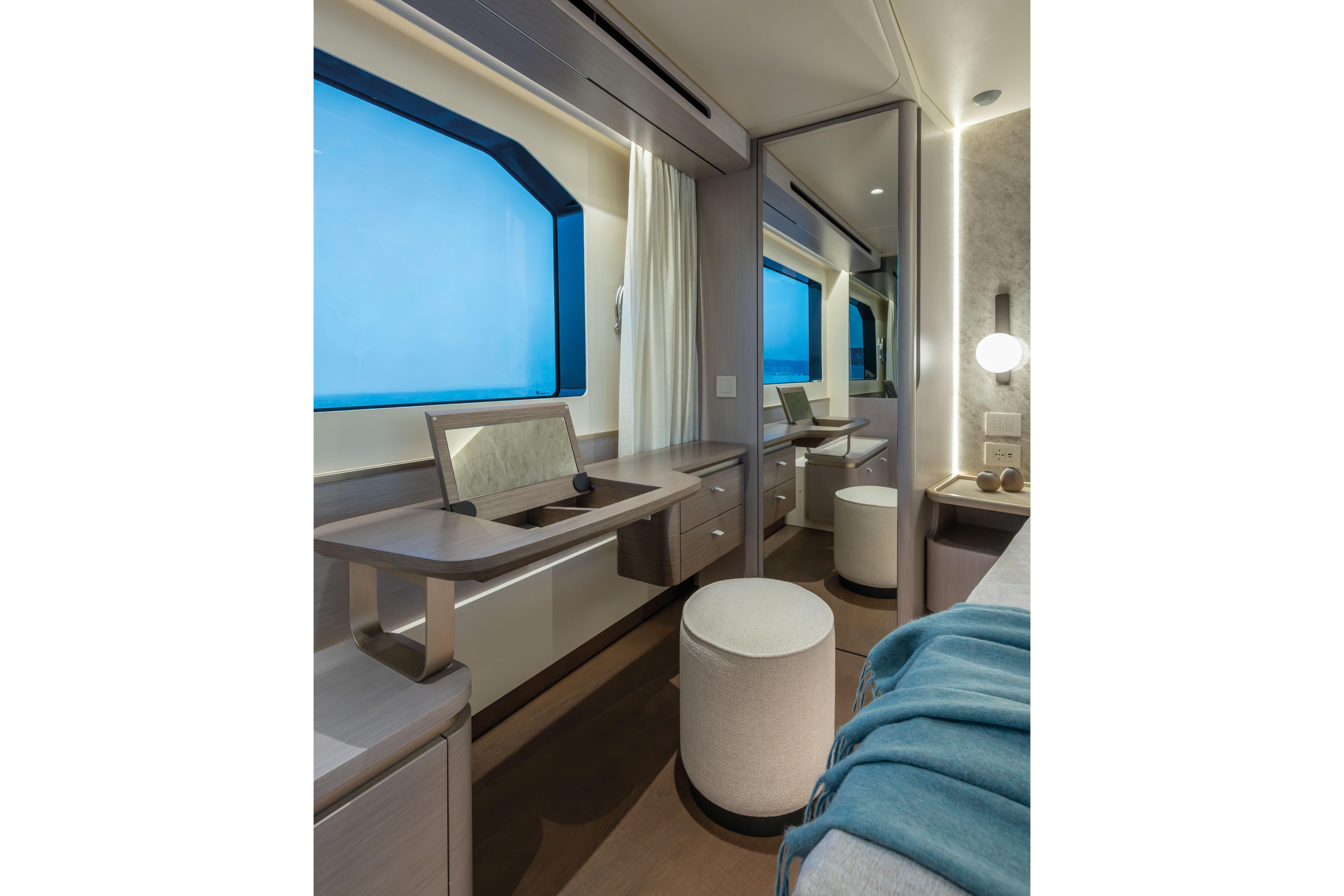 Elegant yacht interior with large window, vanity desk, and stool.