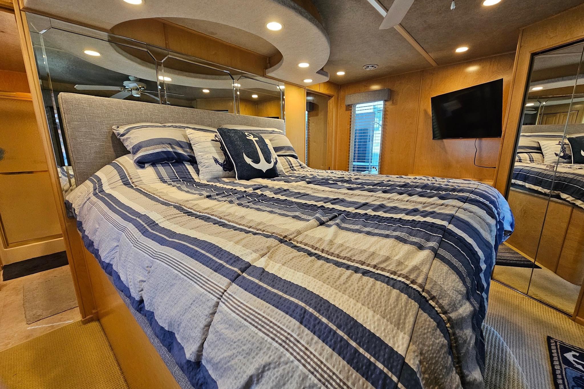 Luxurious bedroom in a 2001 Sumerset 16x79 houseboat with nautical-themed decor.