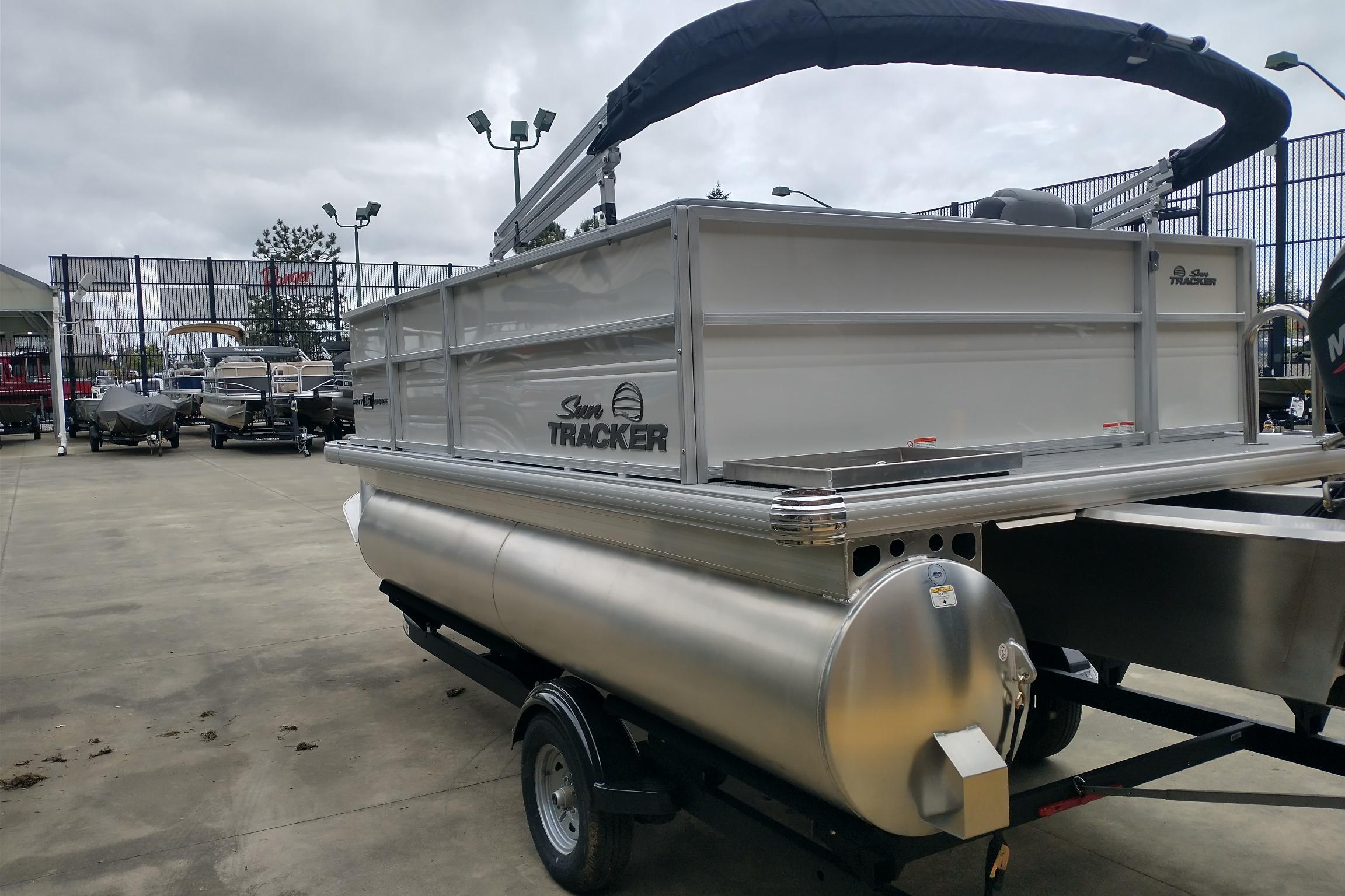 2026 Sun Tracker Party Barge 16 DLX pontoon boat on trailer in outdoor showroom.