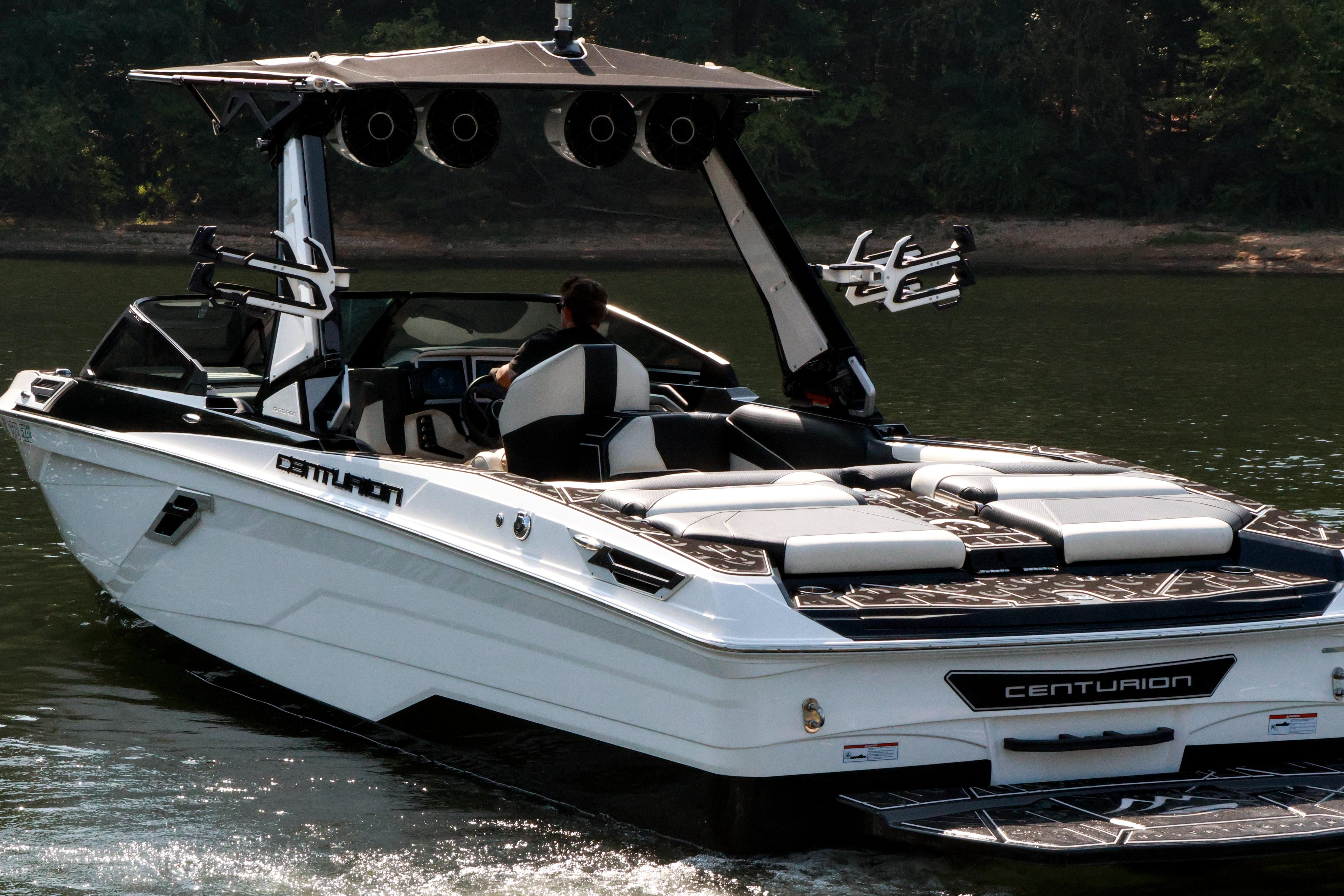 2022 Centurion Ri265 boat cruising on a calm lake with lush greenery in the background.