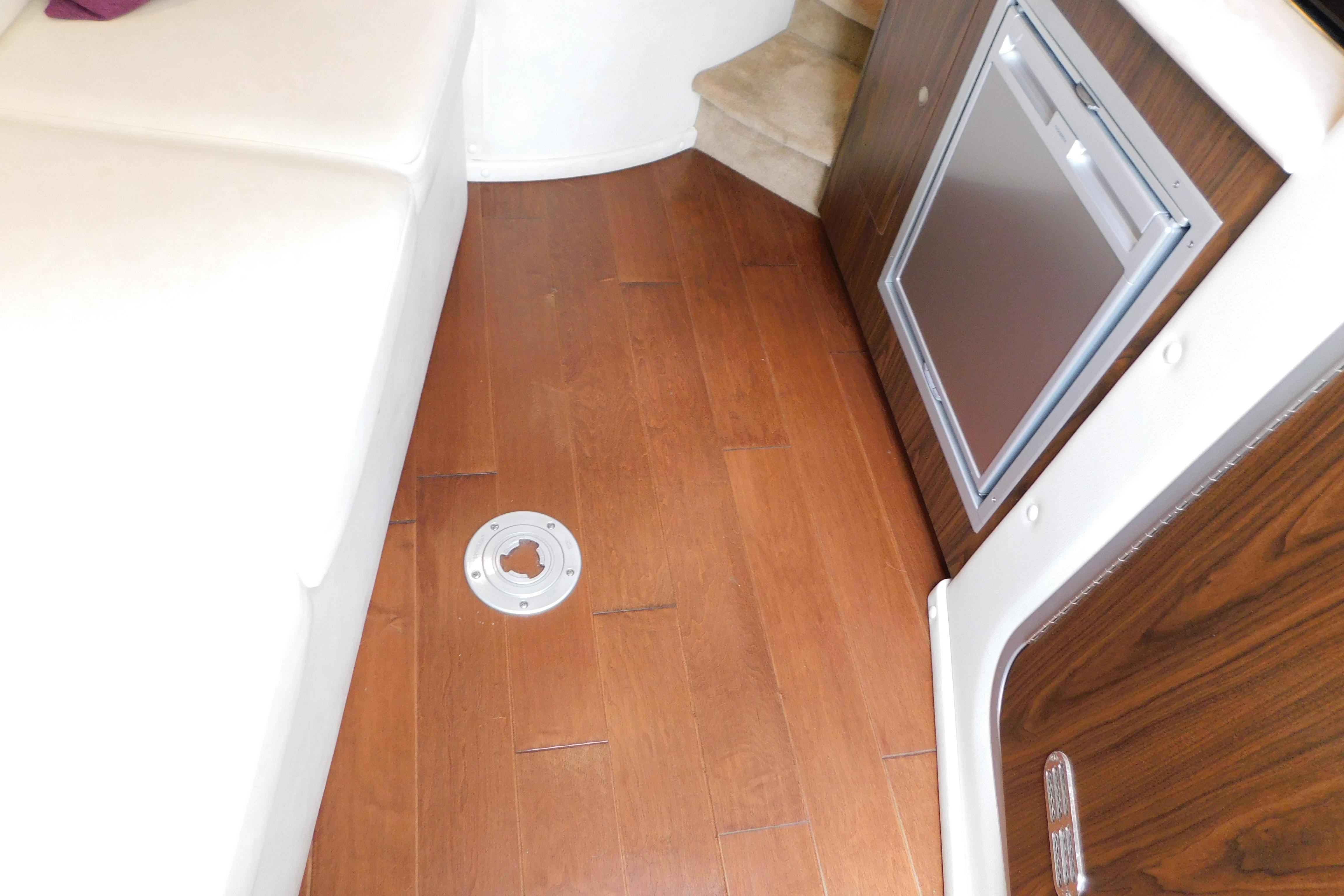 Interior of 2017 Rinker EX 320 boat with wood flooring and compact fridge.