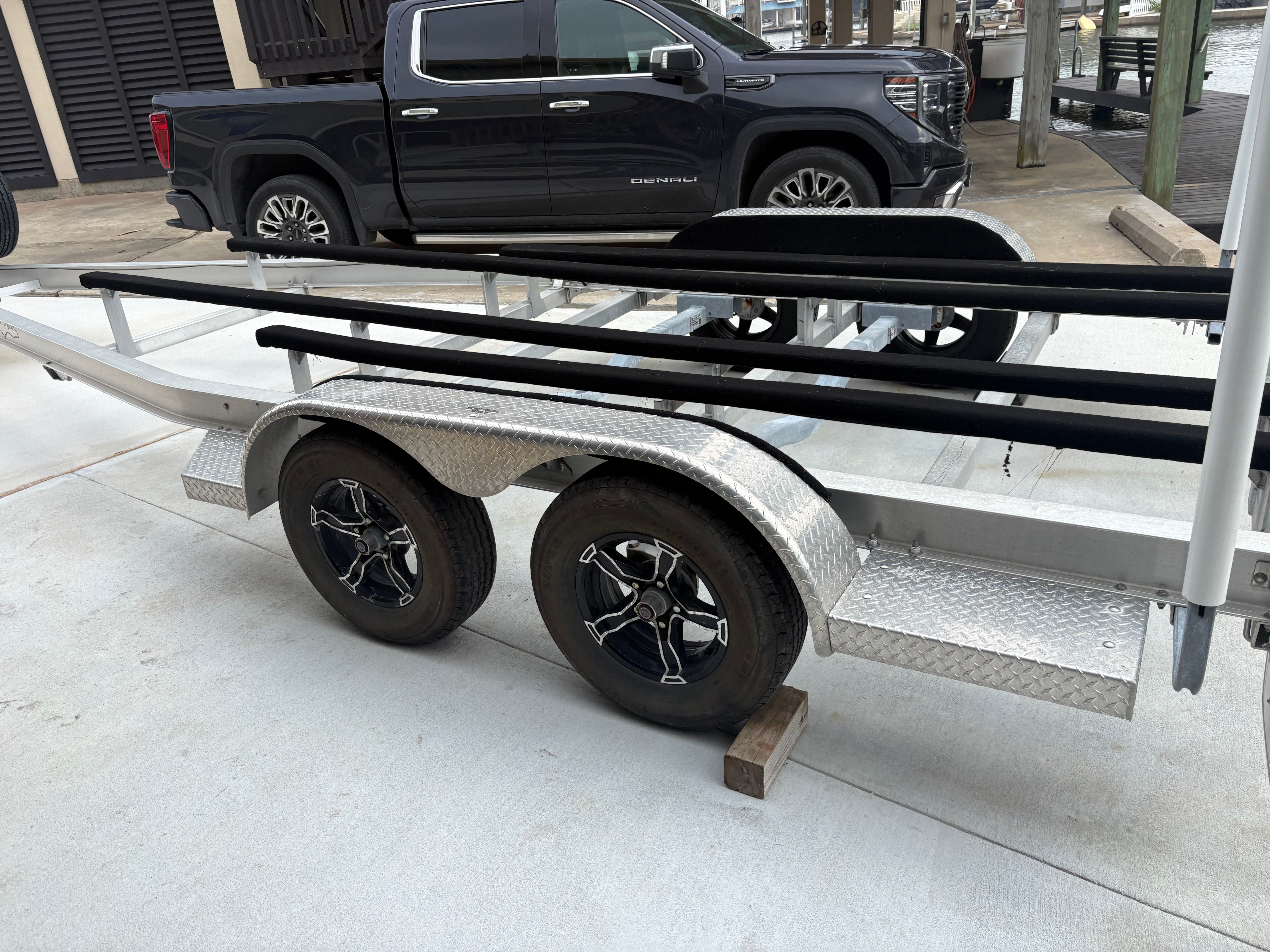 Trailer for a Shallow Sport 24 Sport boat, parked next to a black pickup truck.