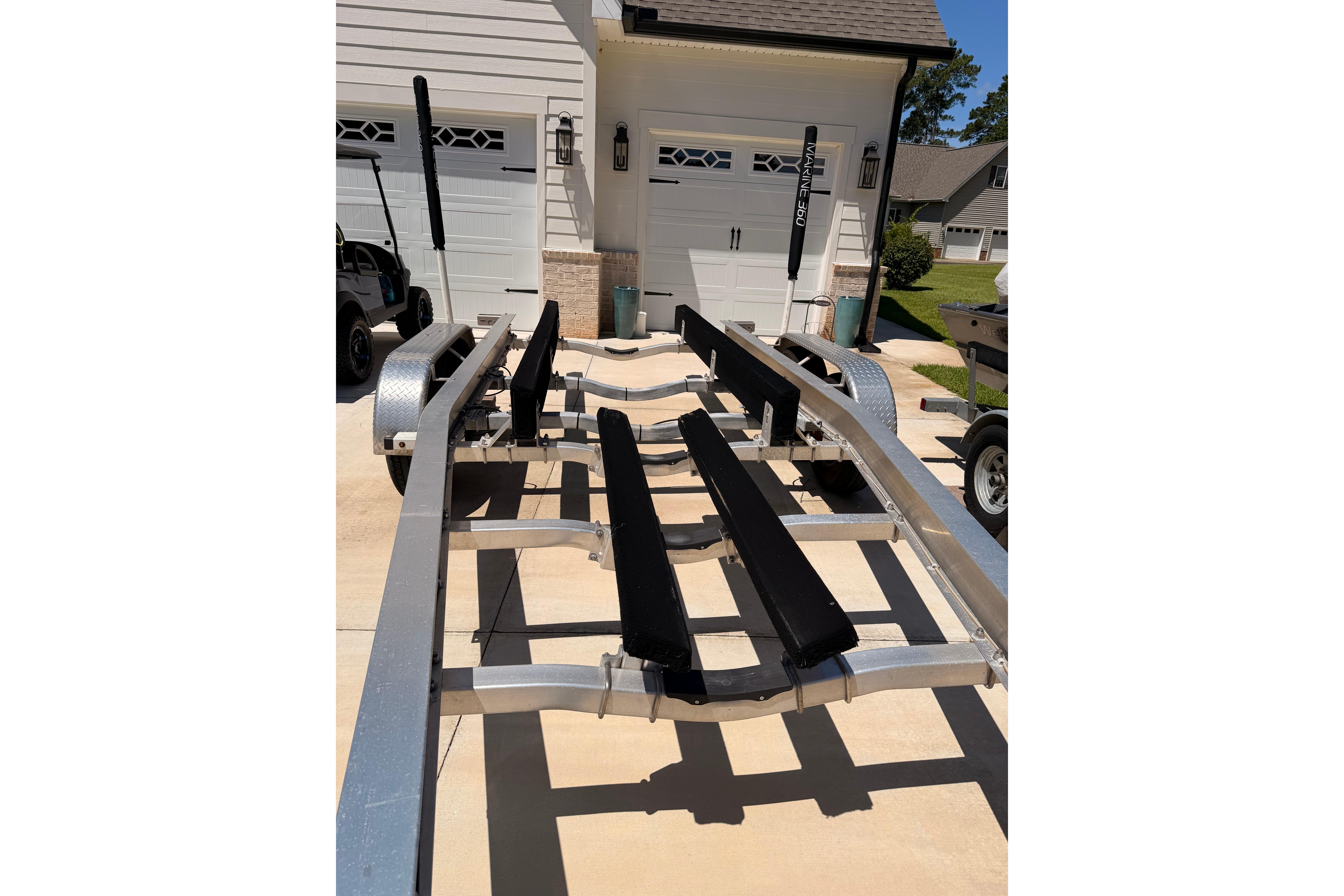 Boat trailer for 2024 Sea Hunt Gamefish 27 Coffin Box, parked in driveway.