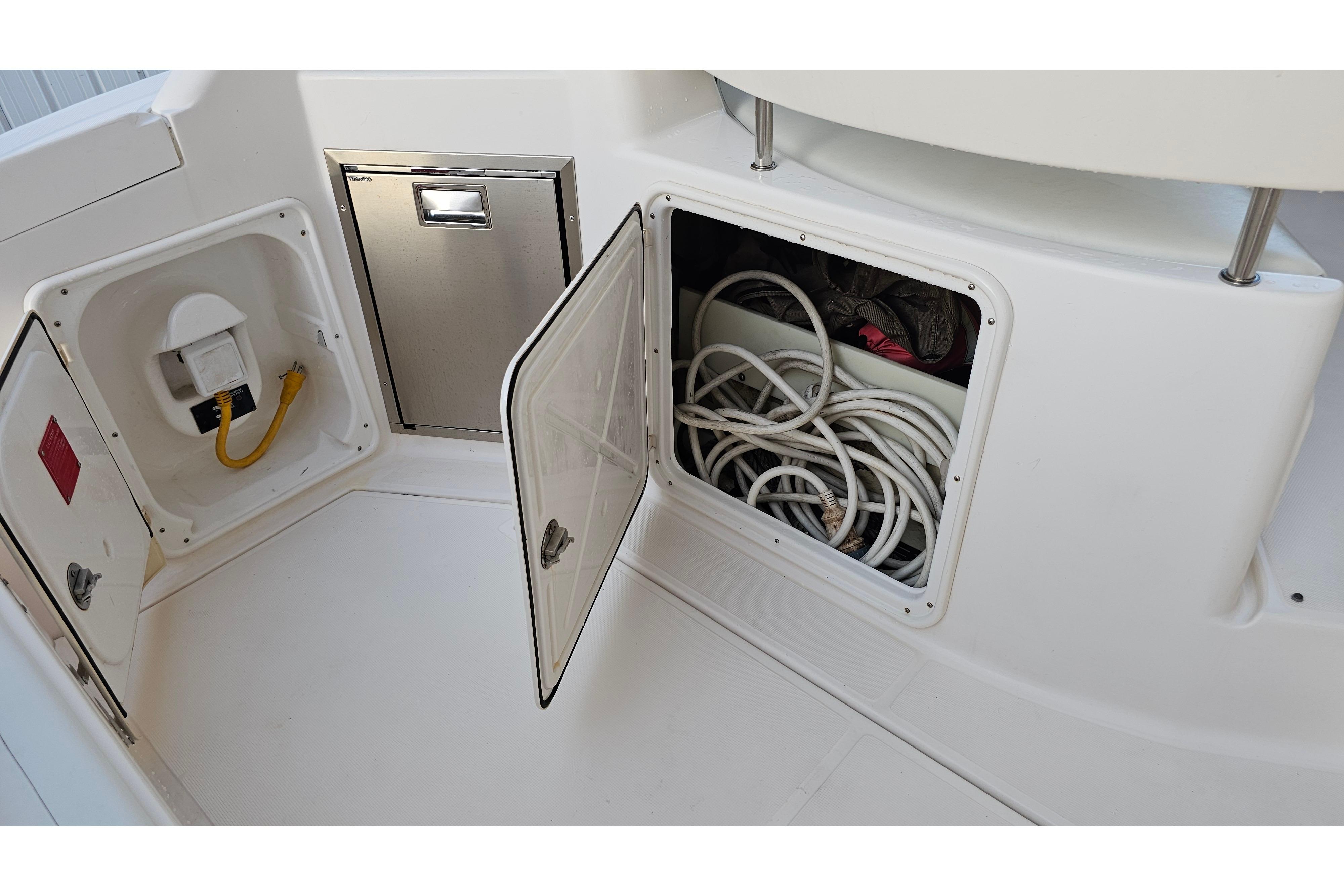 2005 Regal 3060 Window Express boat storage compartments with coiled cables and electrical outlet.