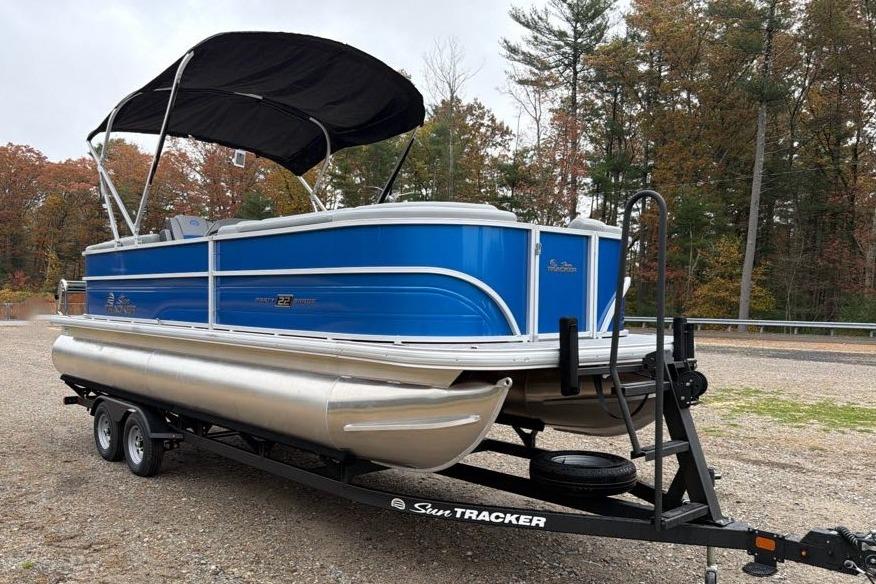 2026 Sun Tracker Party Barge 22 DLX pontoon boat on trailer, parked outdoors.