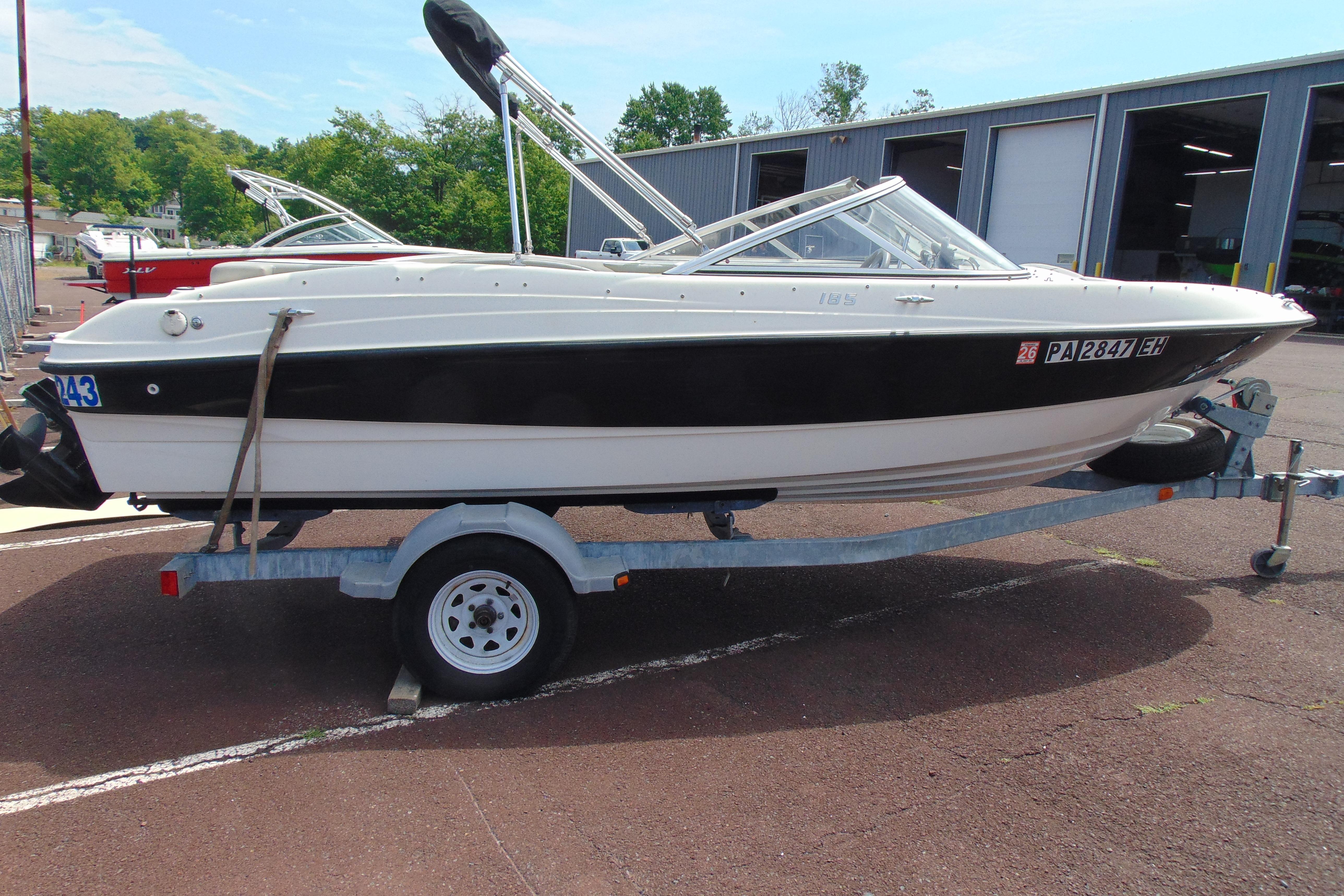 2012 Bayliner 185 Bowrider on trailer, parked outdoors near a warehouse.
