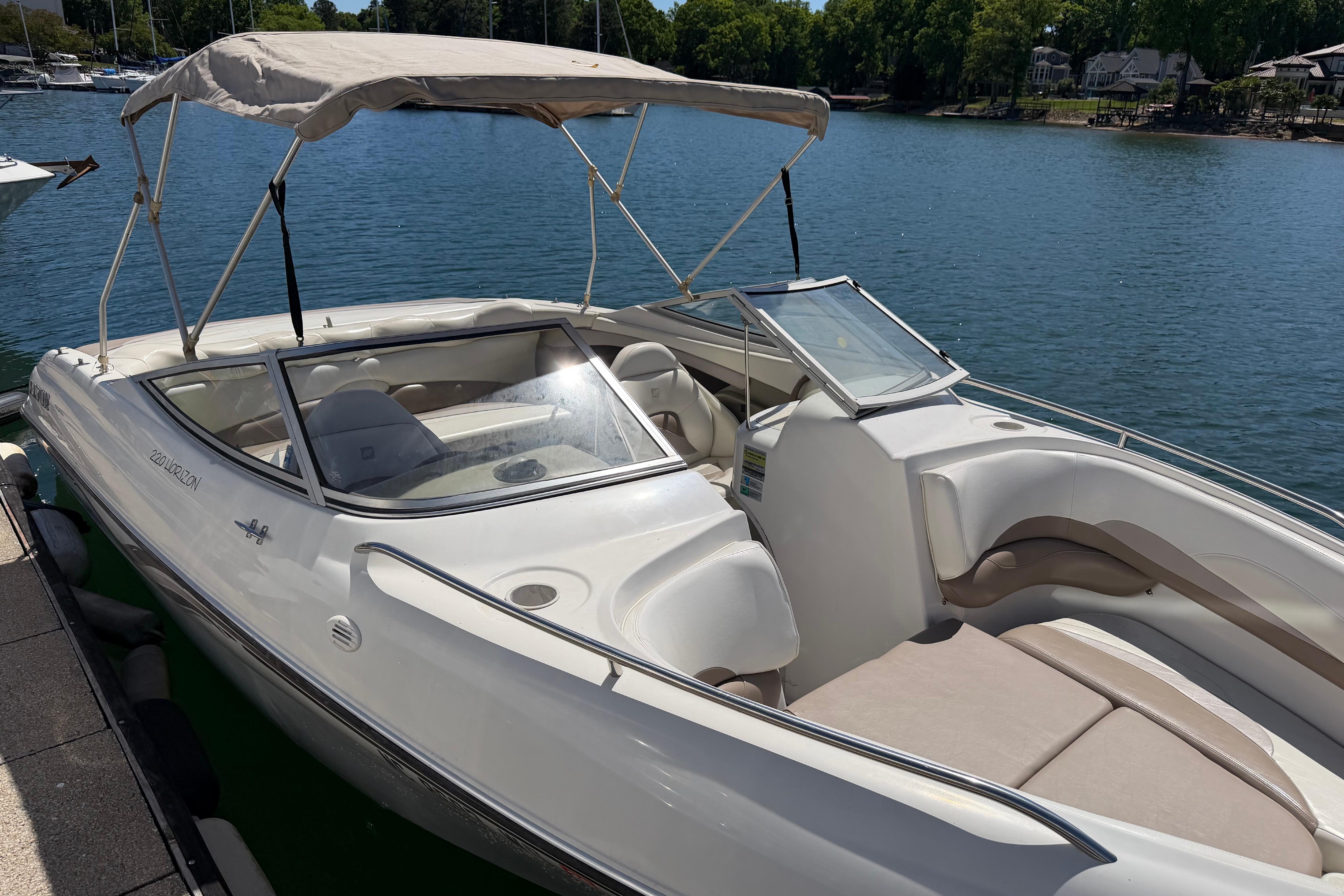 1998 Four Winns 220 Horizon boat docked on a sunny lake with canopy.