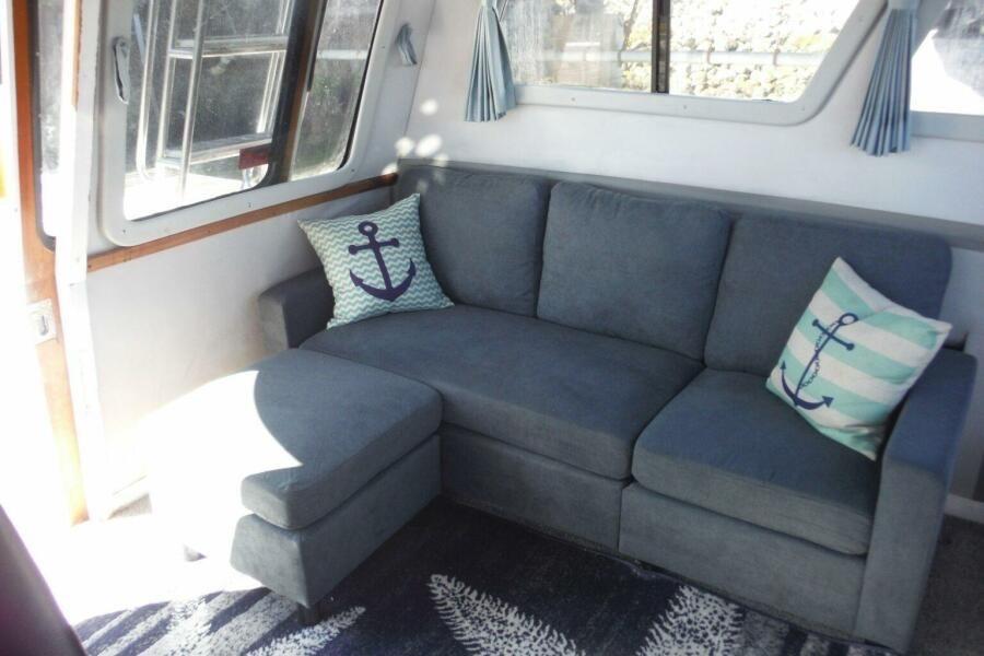 Cozy interior of 1990 Mediterranean Sport Fish with blue sofa and nautical pillows.