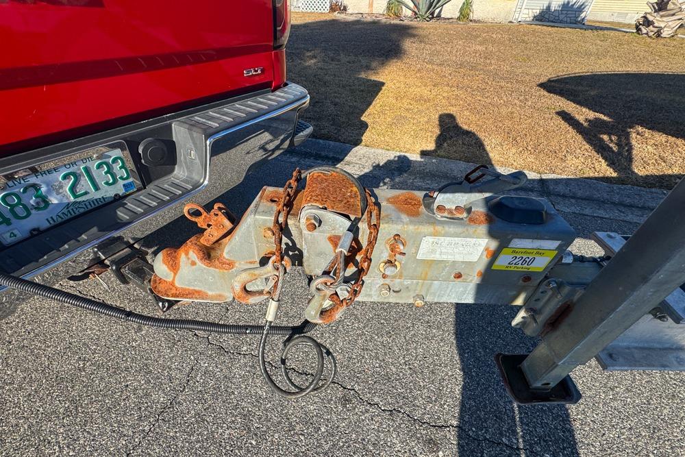 Red truck towing a rusted trailer hitch, connected to a Formula 292 SR-1, 1989 model.