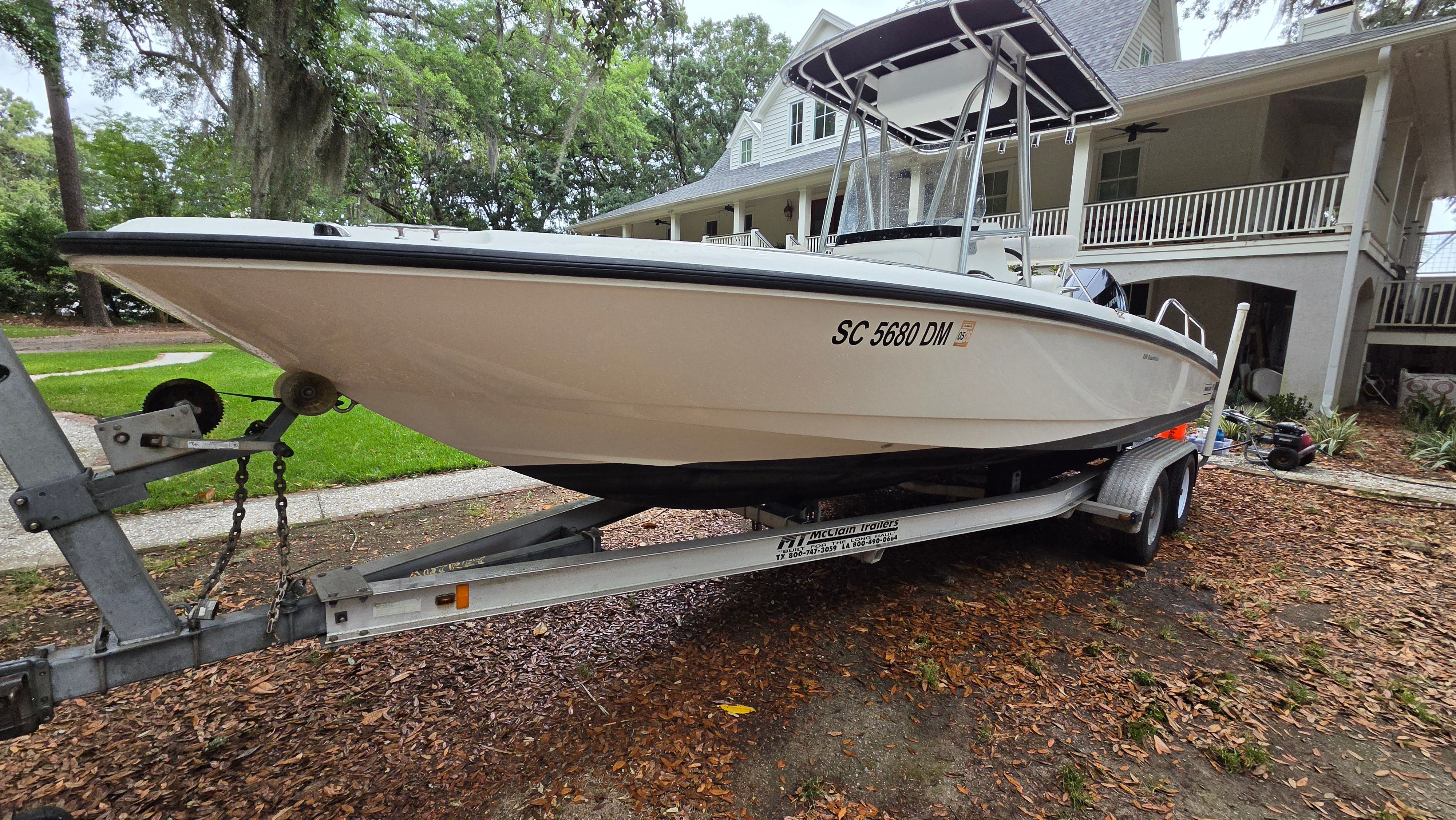 2008 Boston Whaler 230 Dauntless on a trailer parked in front of a house.