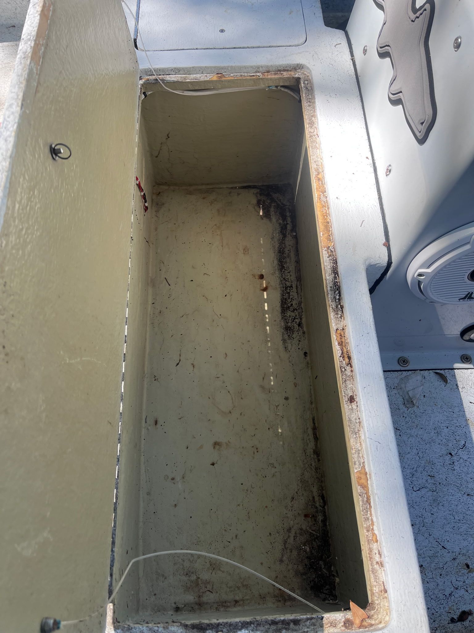 An open storage compartment on a 1974 McKee Craft Skiff, showing a worn interior.