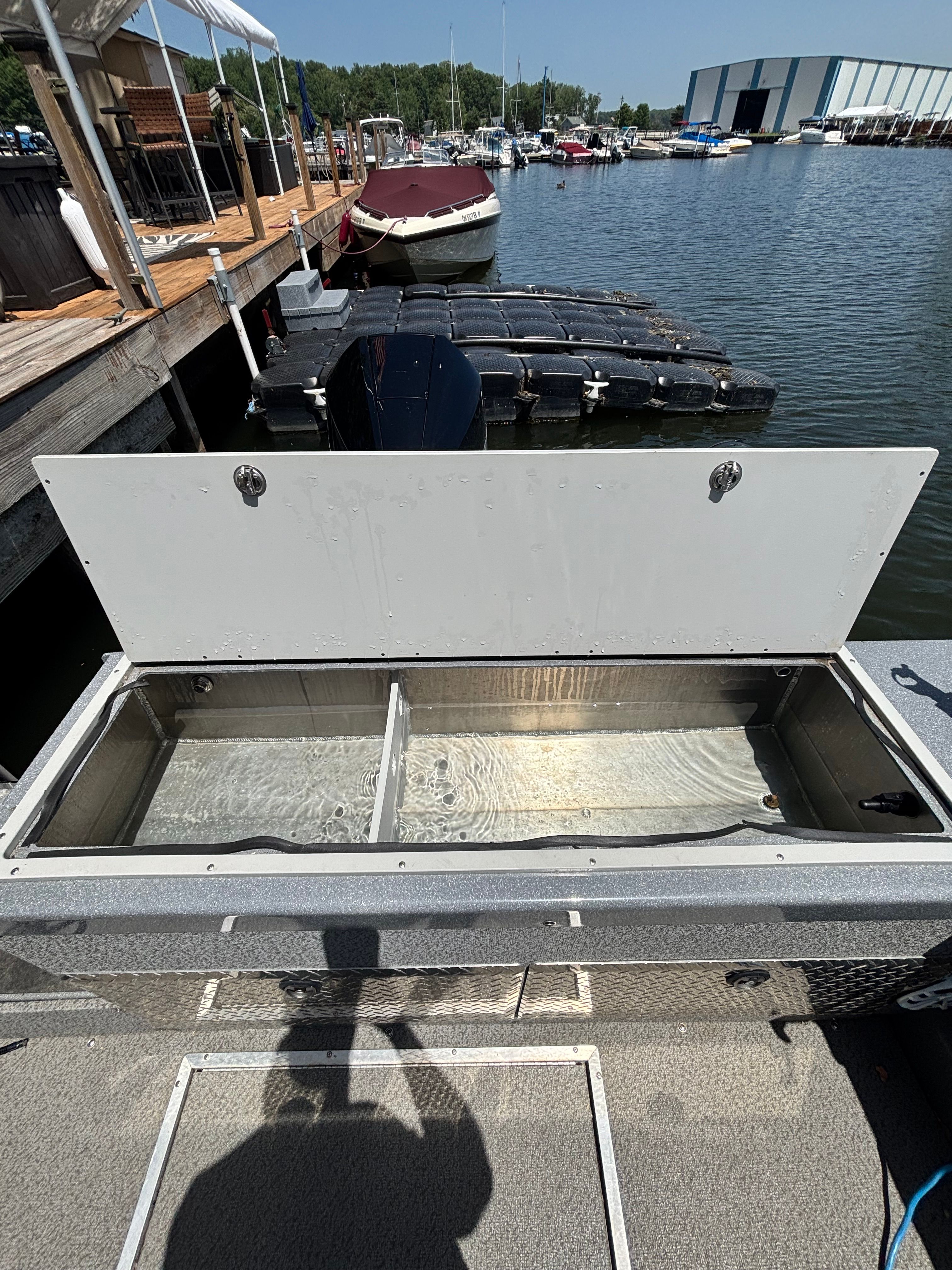 An open storage compartment on a boat at the dock, with water inside.