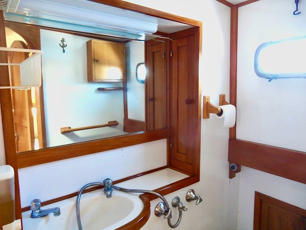 1976 CHB Trawler bathroom with wooden accents, mirror, and sink.