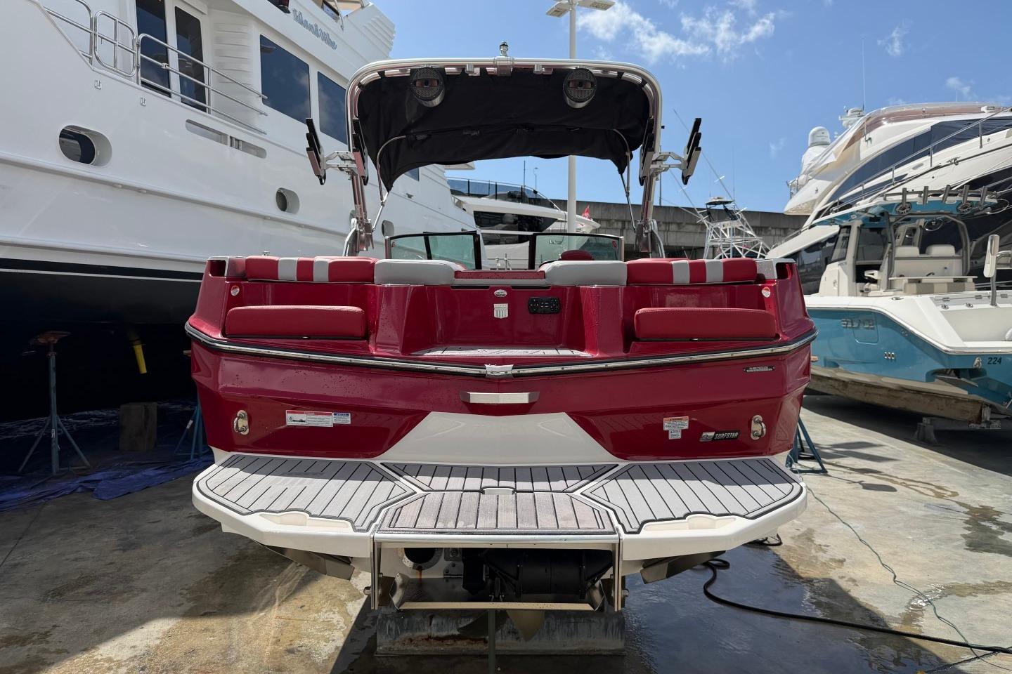 2023 MasterCraft X24 boat with red and white design, docked at a marina.