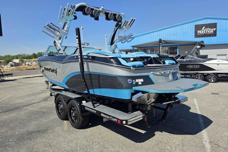 2017 MasterCraft X23 boat on trailer, parked outside dealership under clear blue sky.