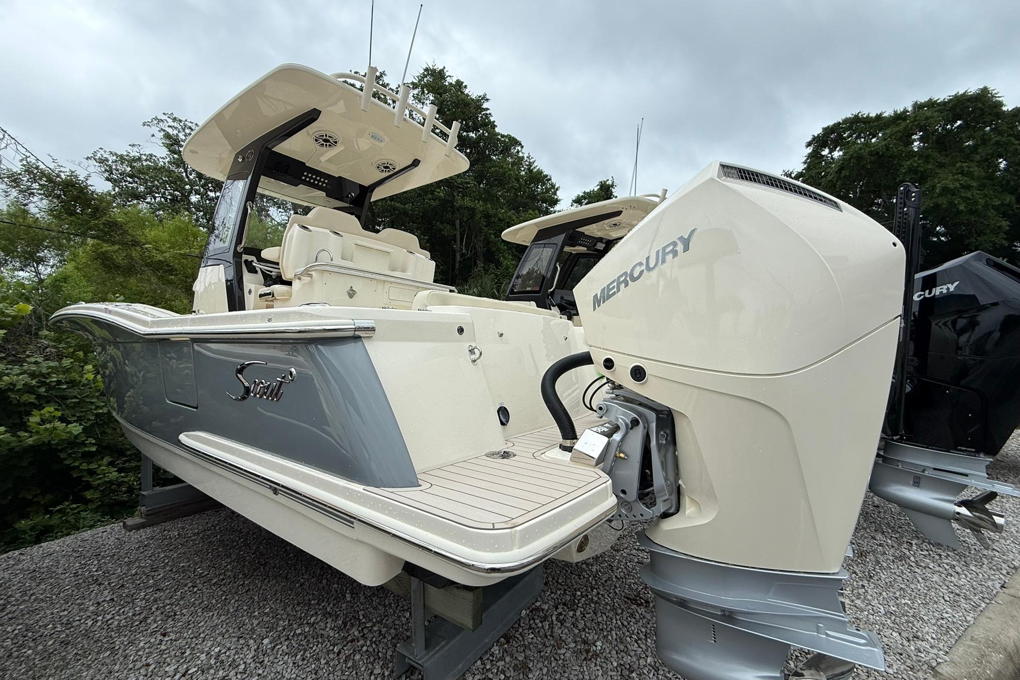 2026 Scout 260 LXF boat with Mercury outboard engine, parked on gravel.