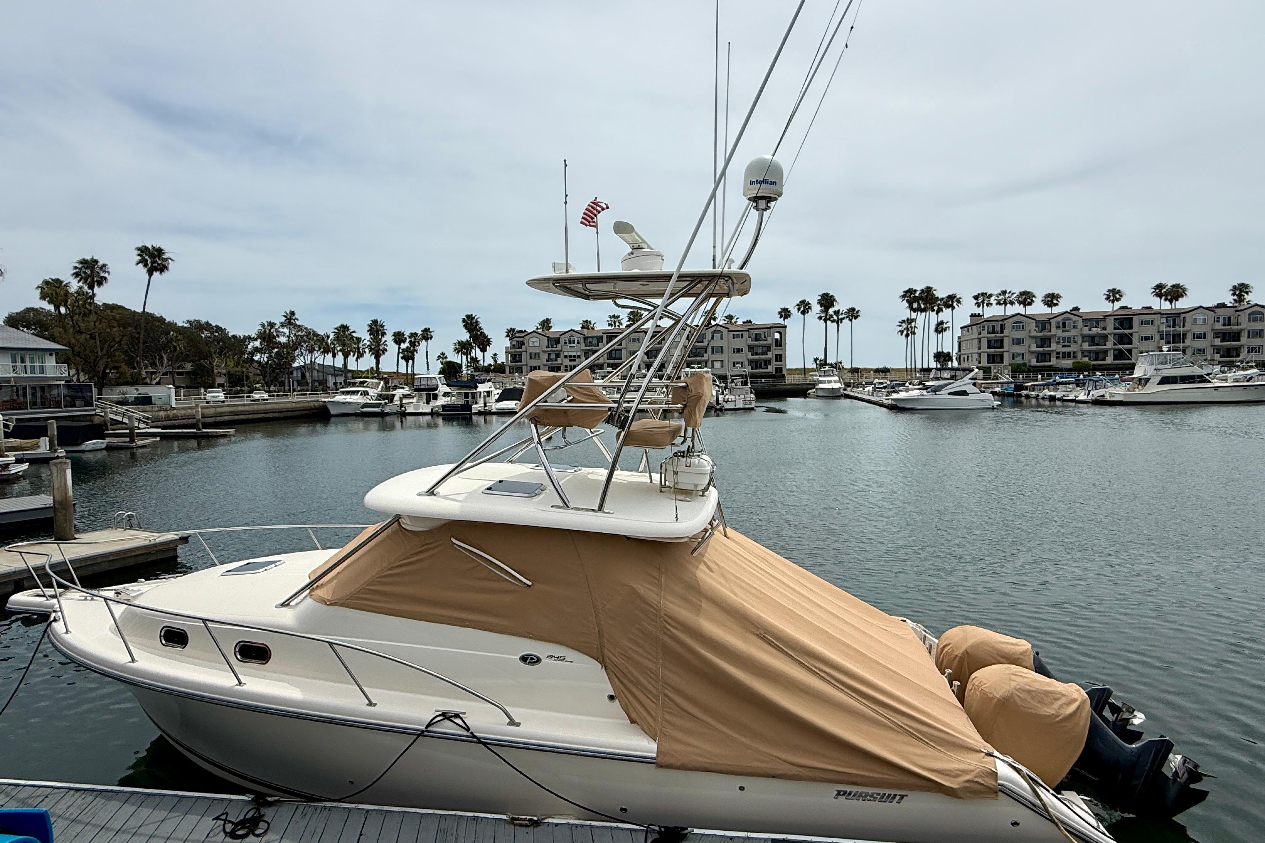 2012 Pursuit OS 345 Offshore boat docked in a marina with palm trees.