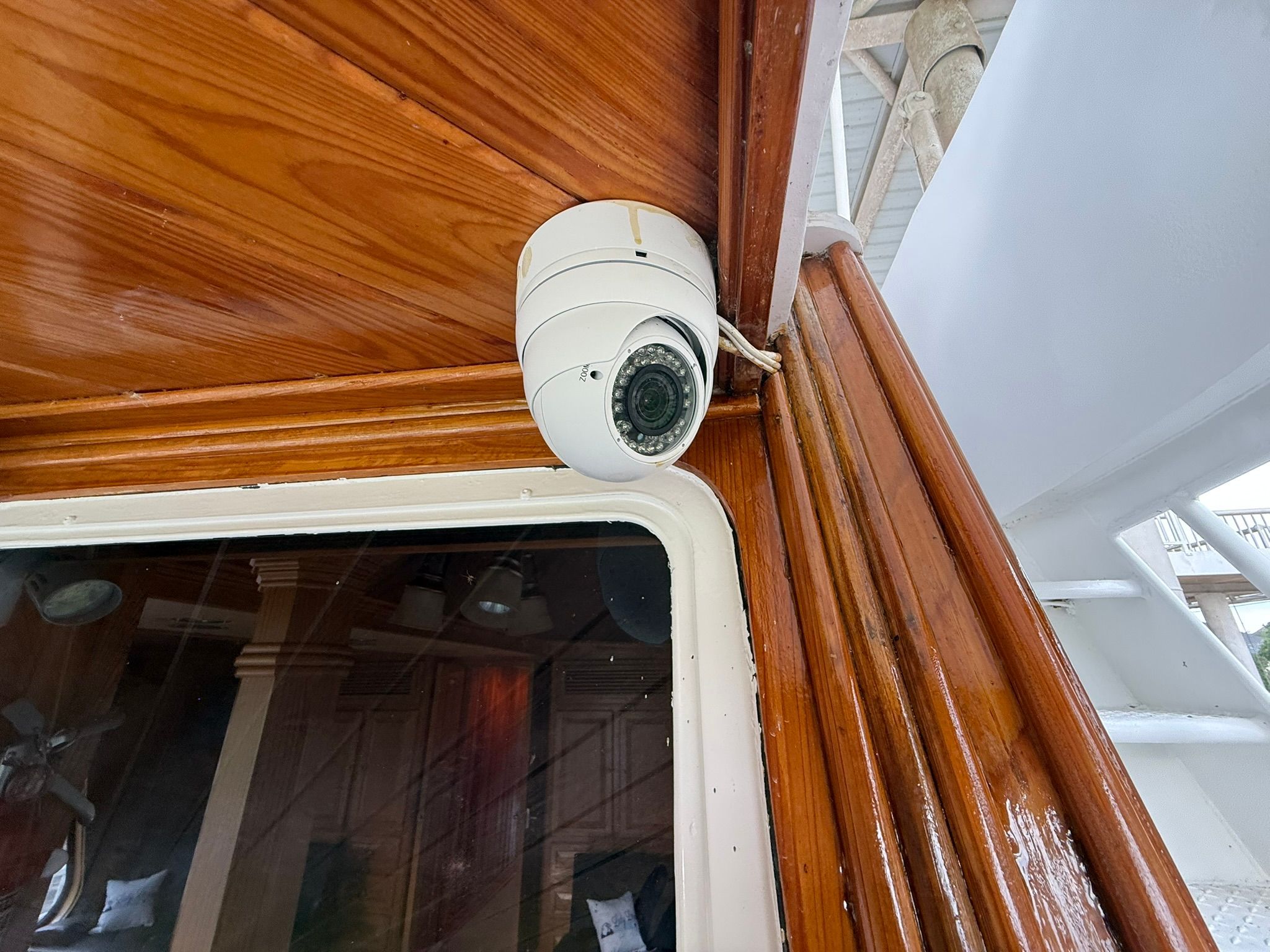 A surveillance camera is mounted on a wooden ceiling on a boat.