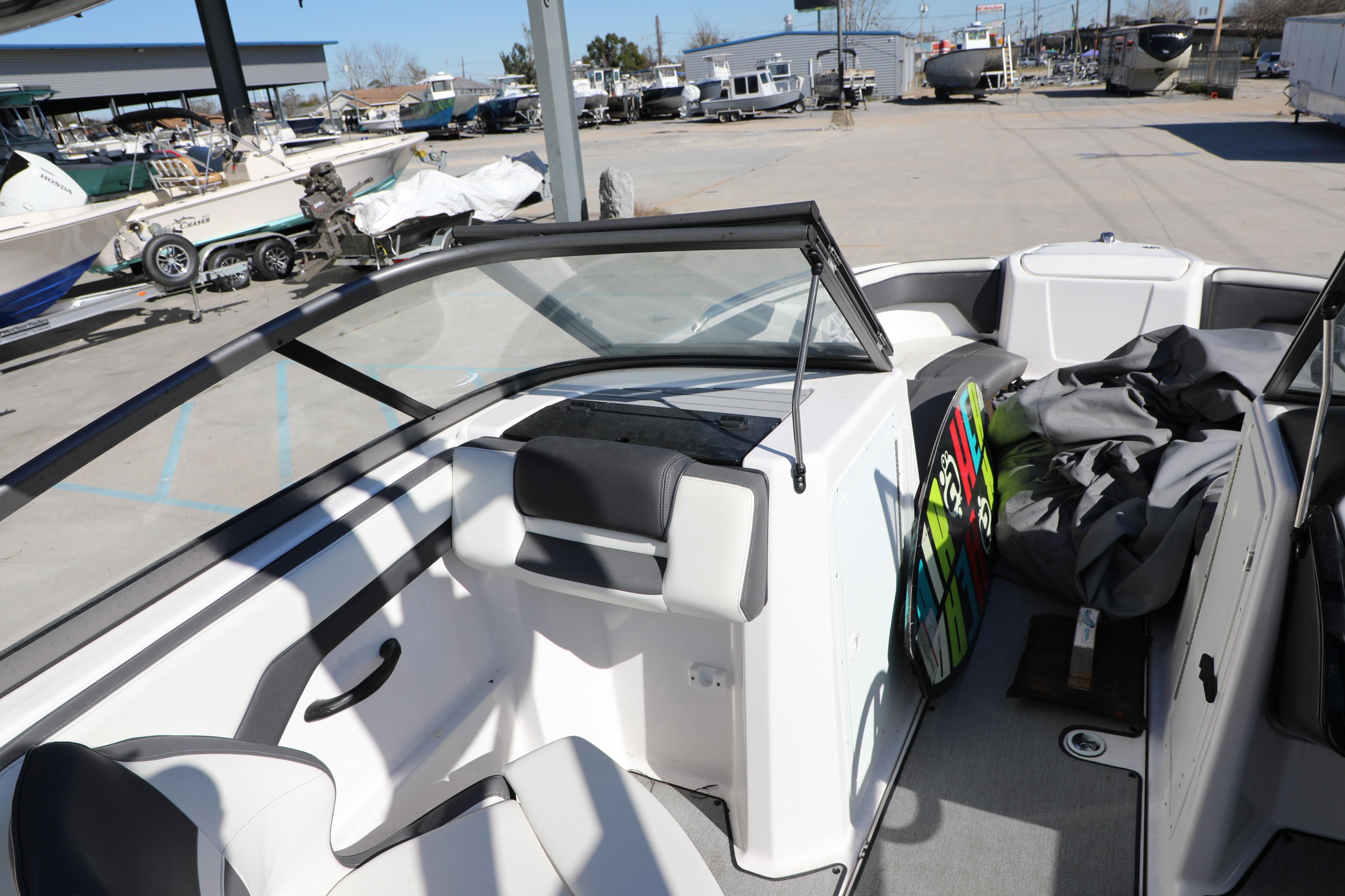 2022 Yamaha Boats AR210 interior with seating and storage, parked in a marina.