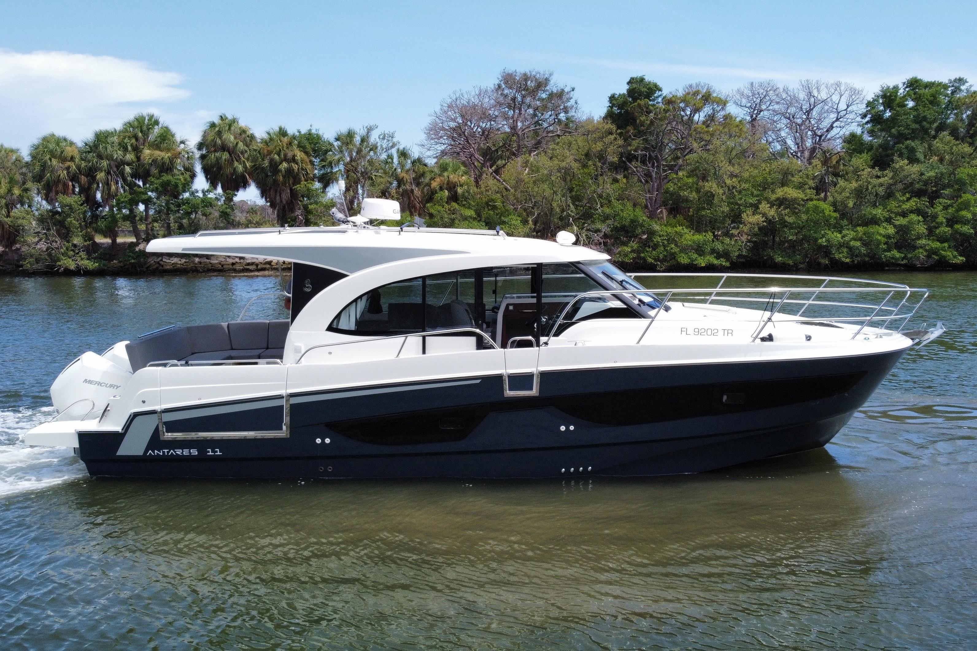 A sleek motorboat, the 2024 Beneteau Antares 11, cruising on calm water with green shoreline.