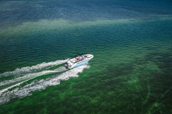 Aerial view of 2025 Hurricane SunDeck 235 OB cruising on clear green water.
