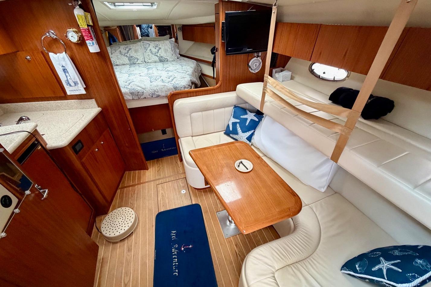 2003 Tiara Yachts 3500 Open interior with cozy seating, wooden table, and nautical decor.