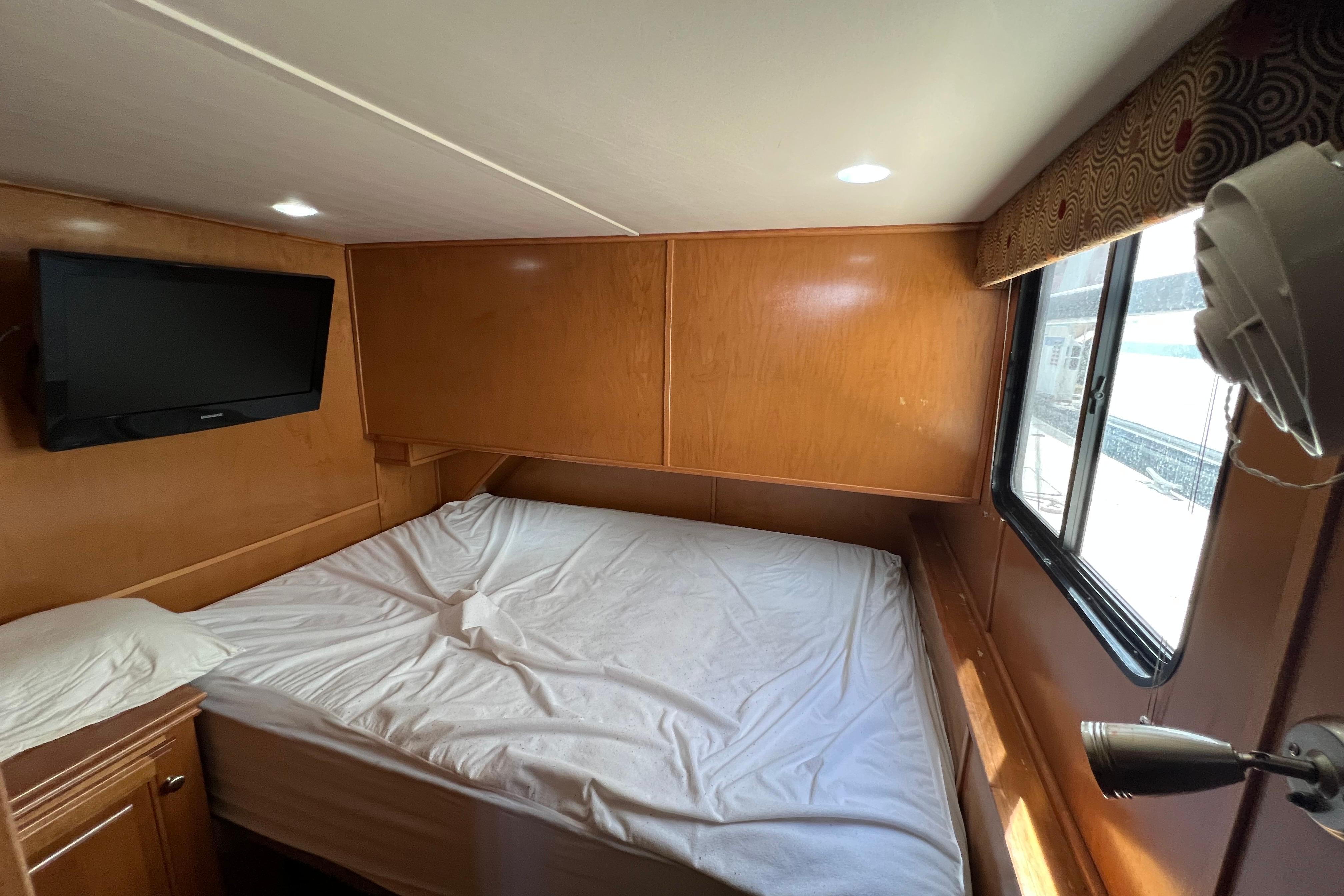 Cozy bedroom interior of 2013 Destination Yacht Lotta Yachta with TV and window view.