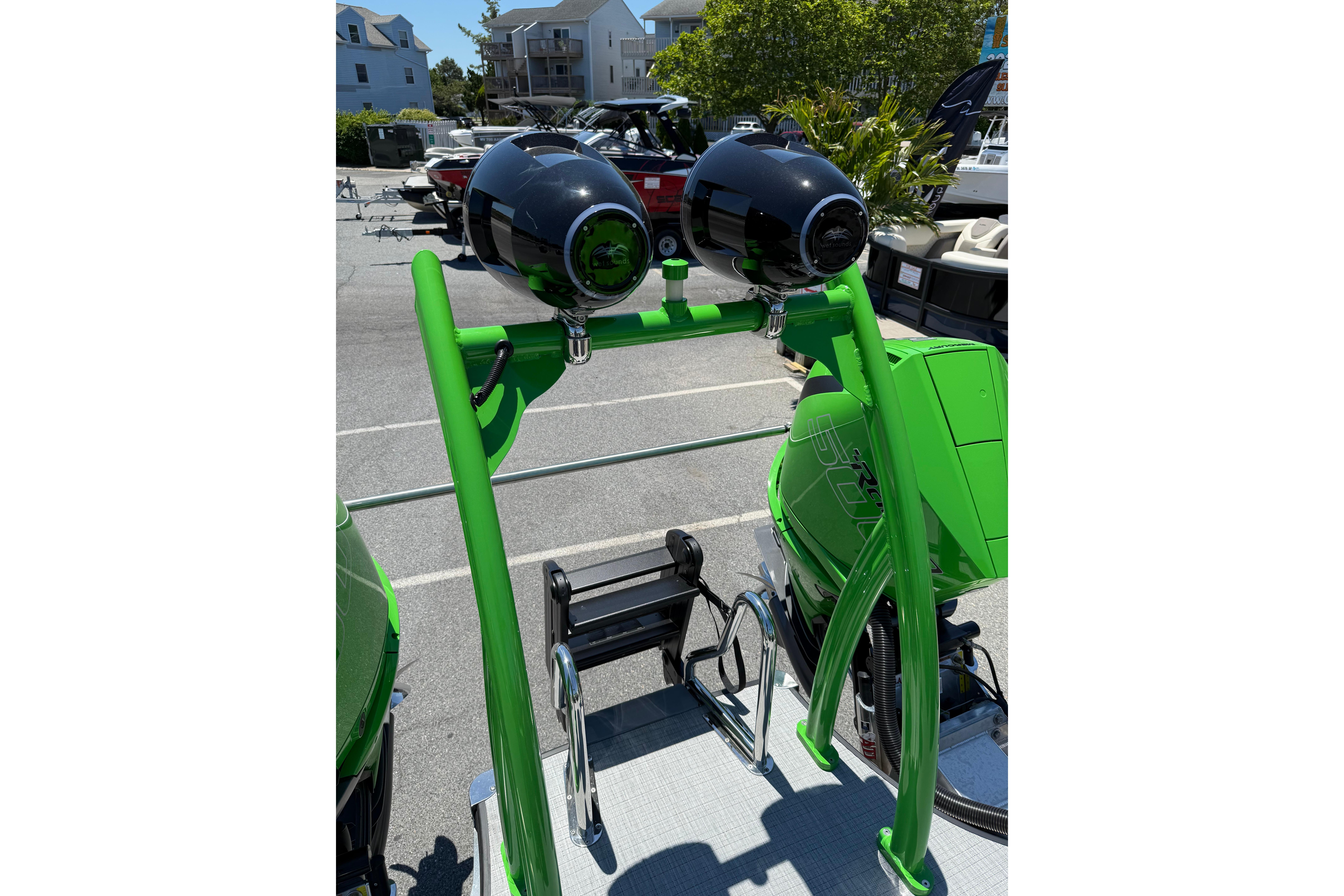 Green Berkshire Sport SLX9 DC 2026 boat with dual speakers and sleek design in a marina setting.