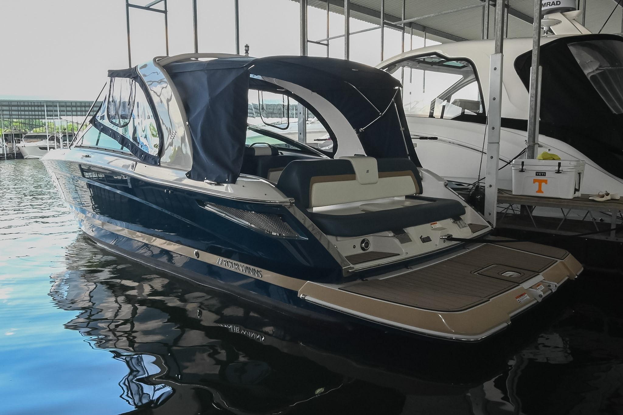 2014 Four Winns H290 boat docked in a marina, featuring a sleek design and canopy.
