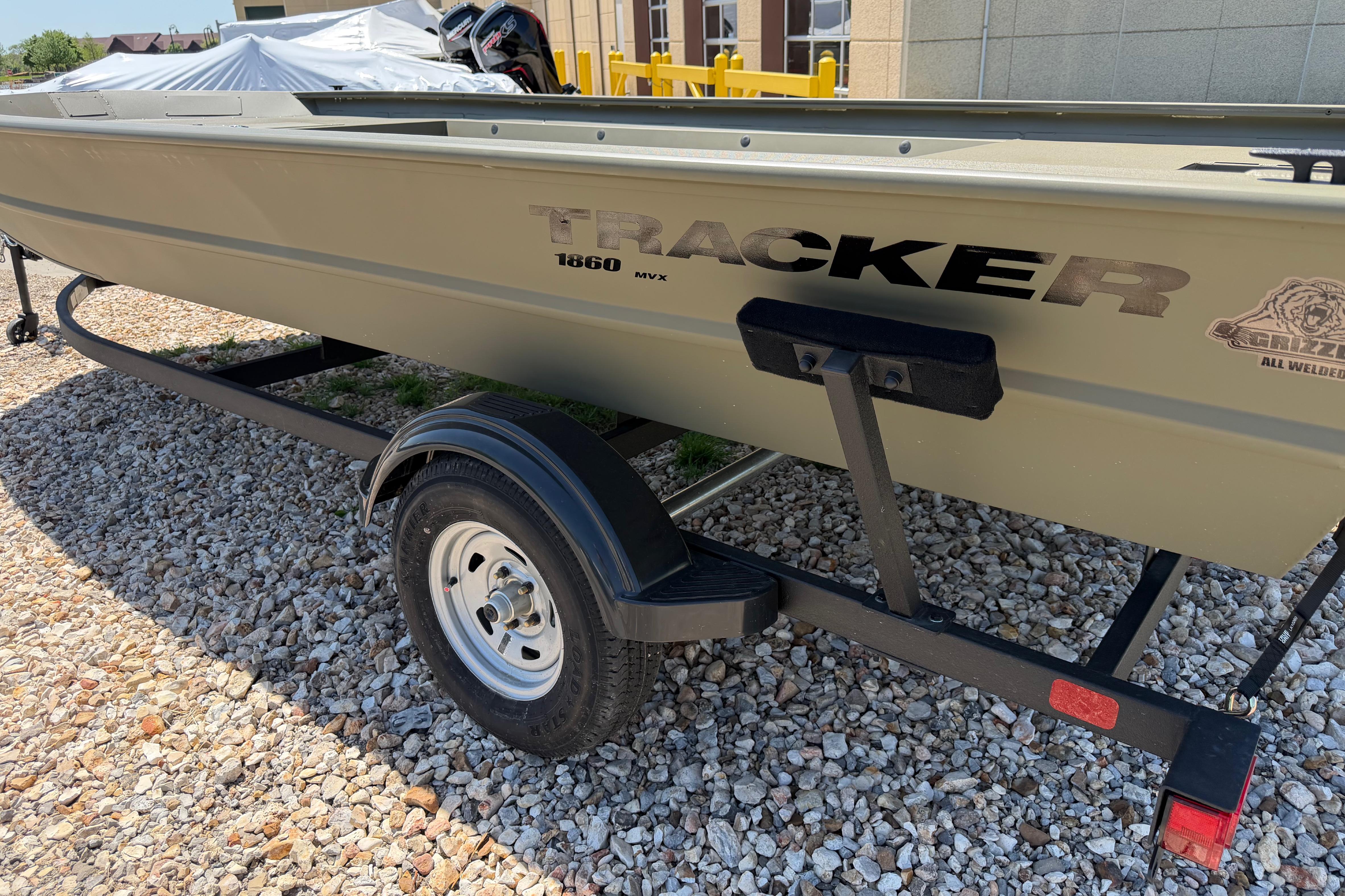 2026 Tracker Grizzly 1860 Utility boat on trailer, parked on gravel.
