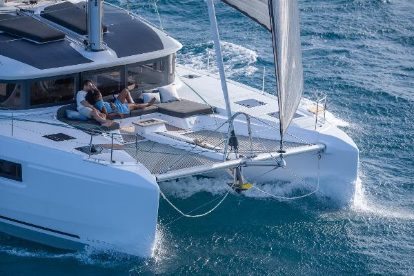 2025 Lagoon 51 ICONIC catamaran sailing with passengers relaxing on deck.