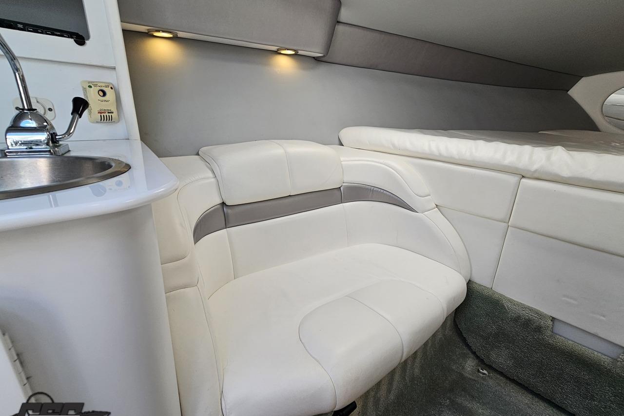 Interior of 2005 Formula 271 FASTech boat, featuring white seating and compact kitchenette.
