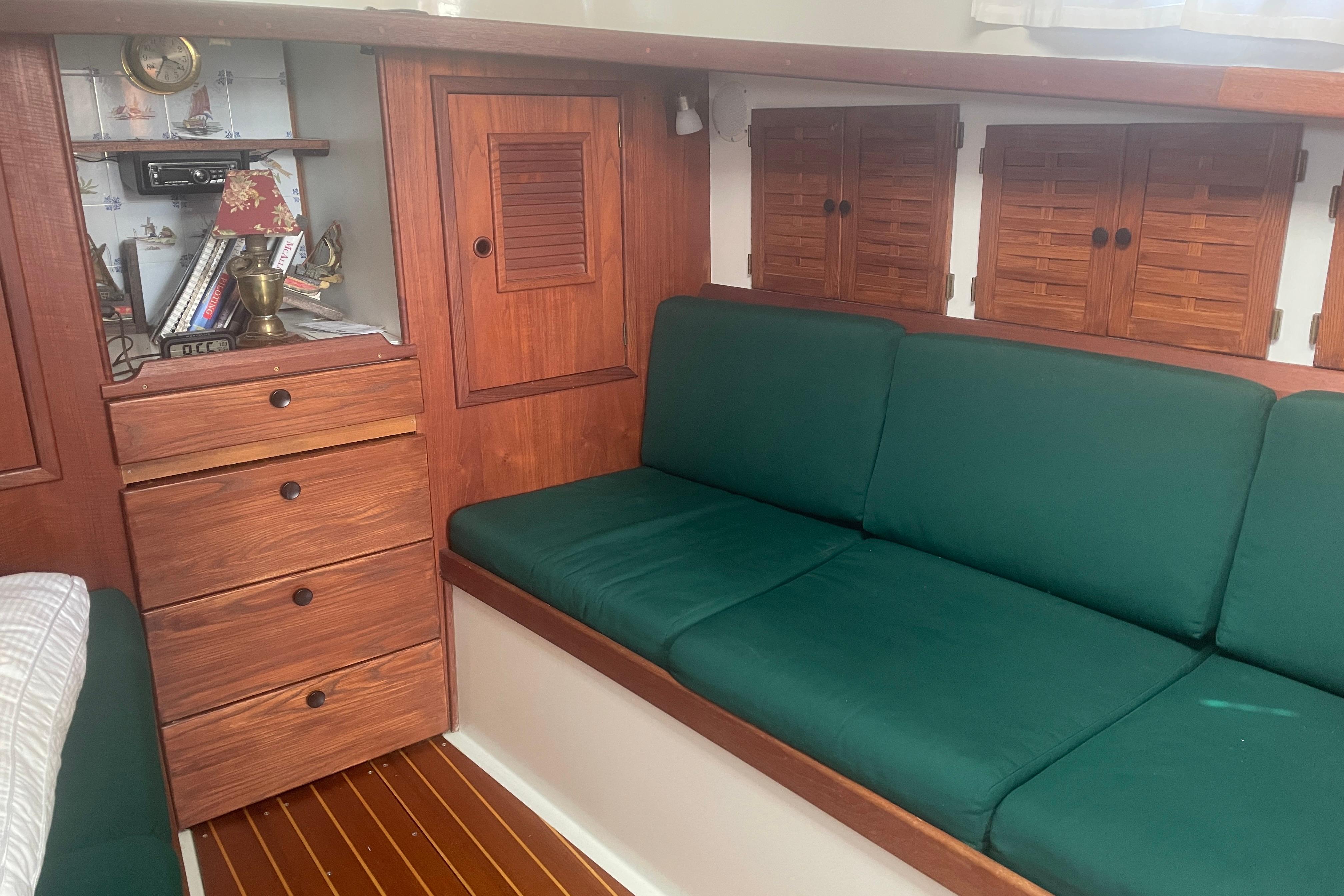 Interior of 1981 Nonsuch 30 Classic sailboat with green cushions and wooden cabinetry.
