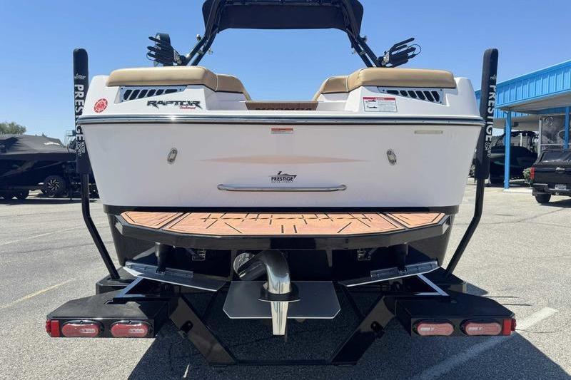 2023 Moomba Mojo Pro boat rear view in parking lot, showcasing swim platform and Raptor engine.