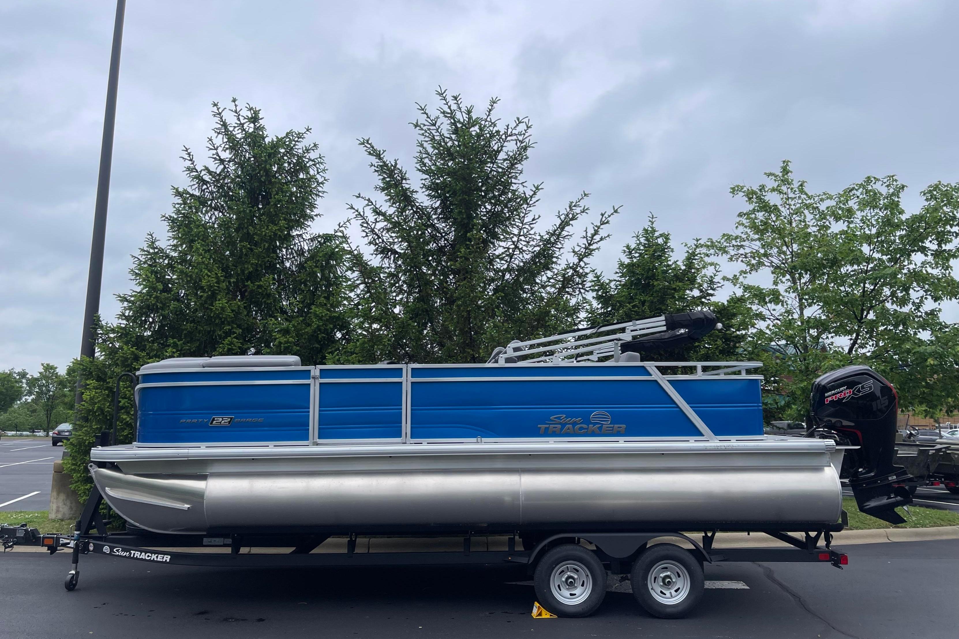 2026 Sun Tracker Party Barge 22 RF DLX pontoon boat on trailer in parking lot.
