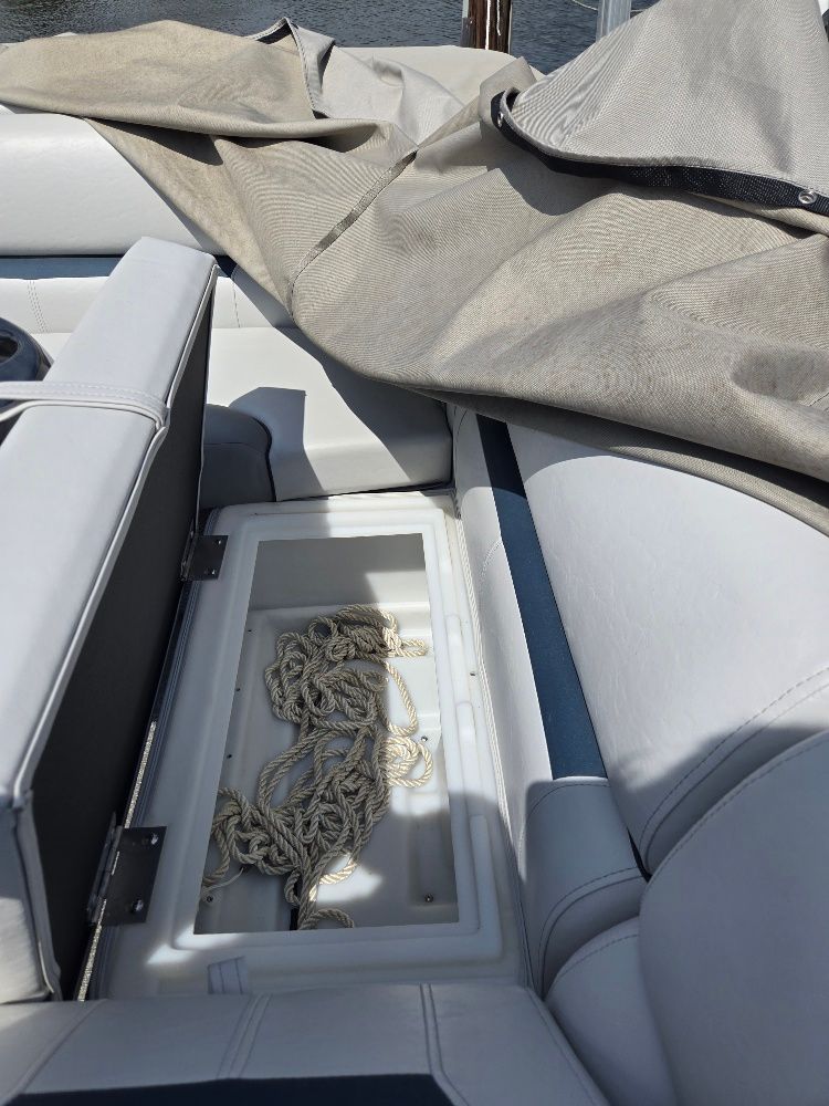 An open storage compartment on a boat with rope inside, surrounded by gray upholstery.