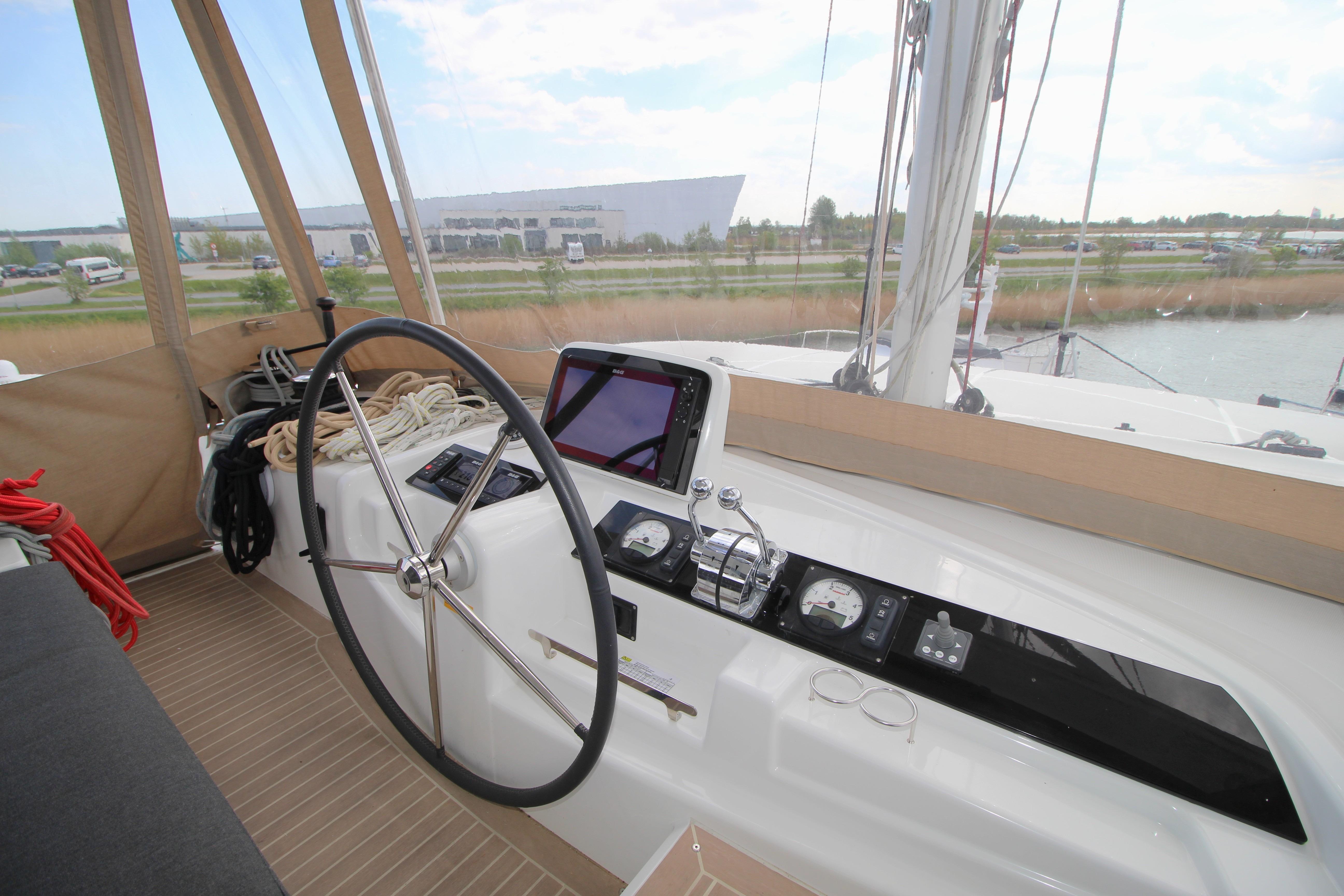 Helm station of 2021 Lagoon 46 catamaran with steering wheel and navigation equipment.