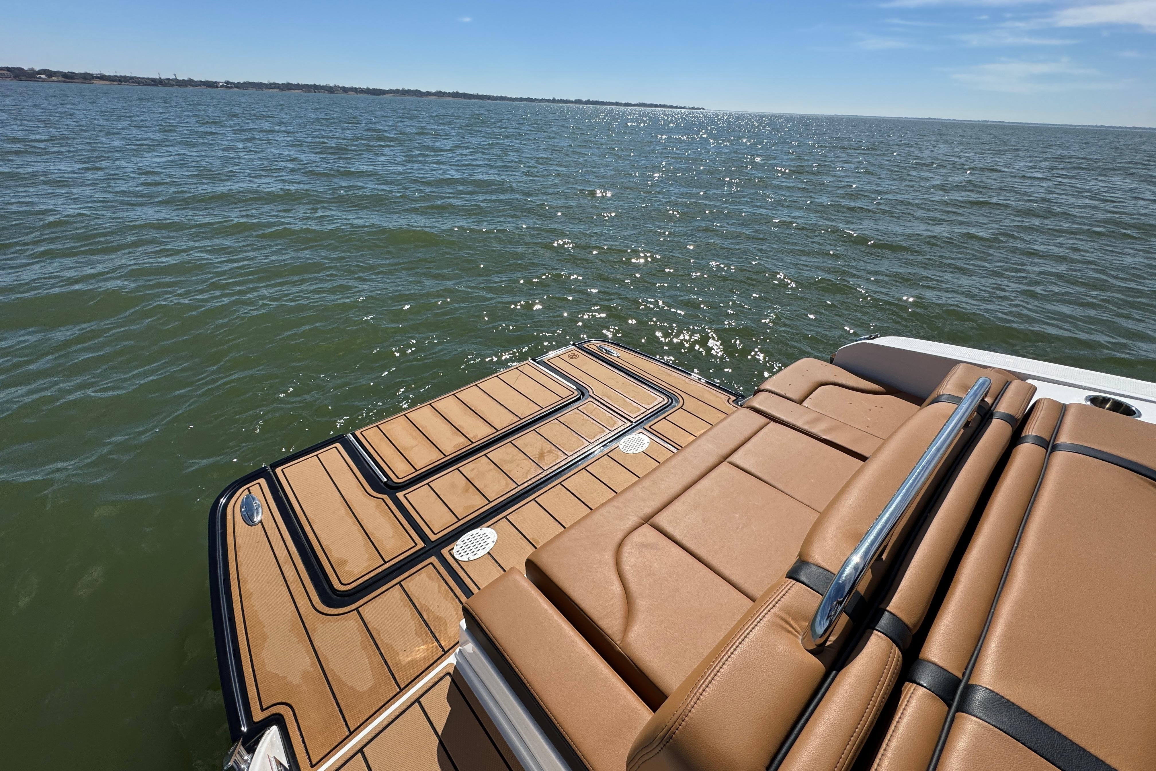 2023 Chaparral 26 Surf boat with tan seating and swim platform on open water.