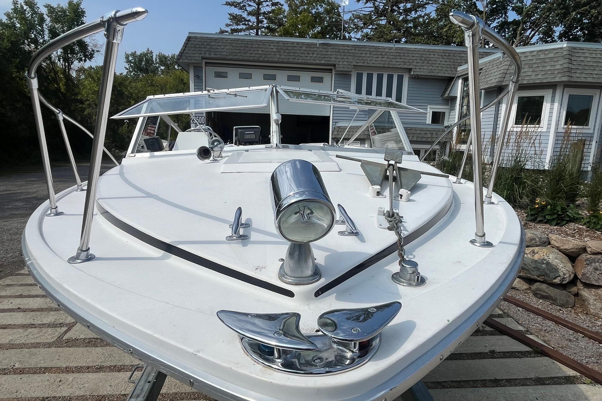 1975 Bertram 26 Moppie boat docked near a modern house, showcasing sleek design.