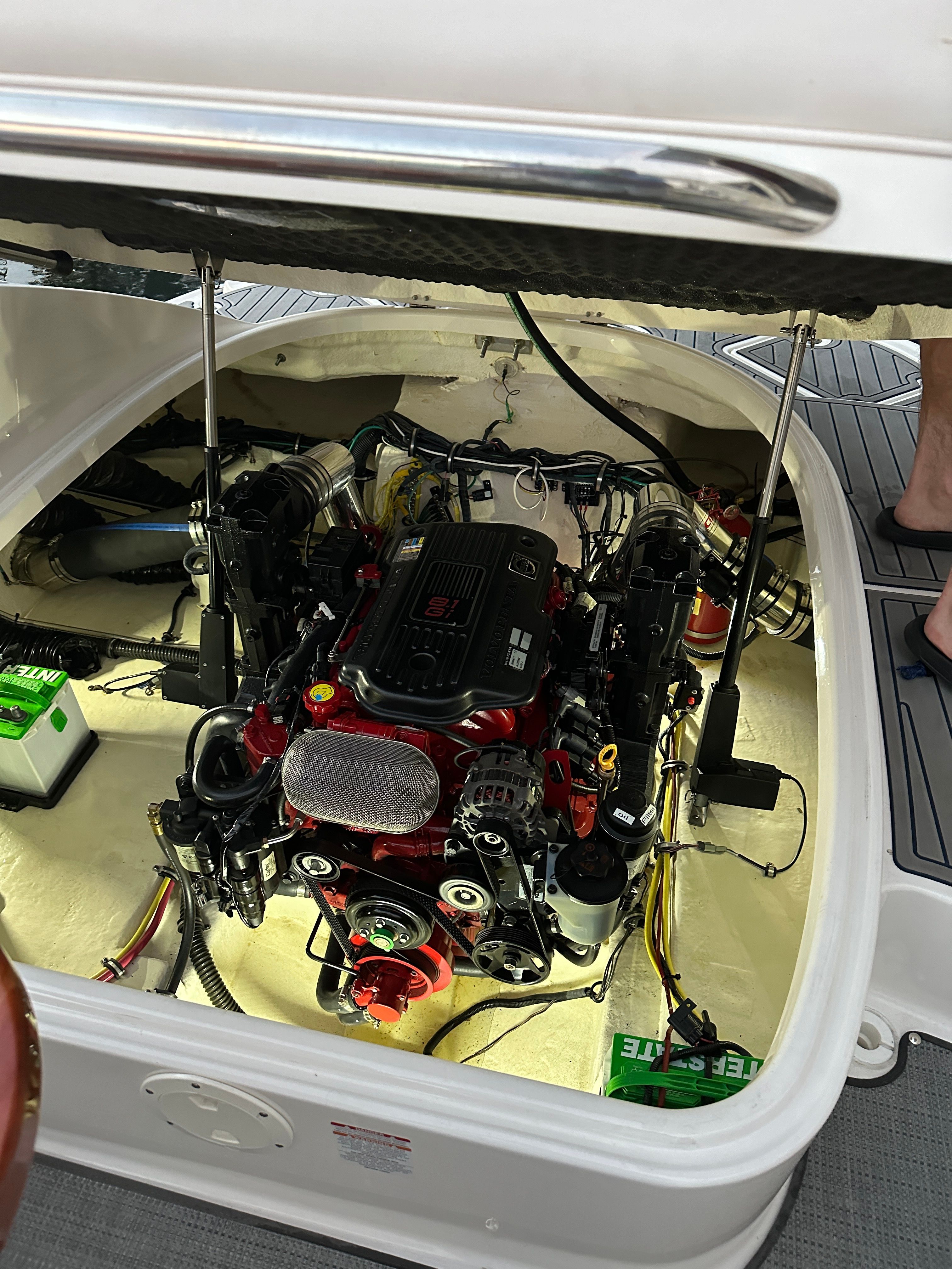 An open engine compartment of a boat with an engine and batteries.