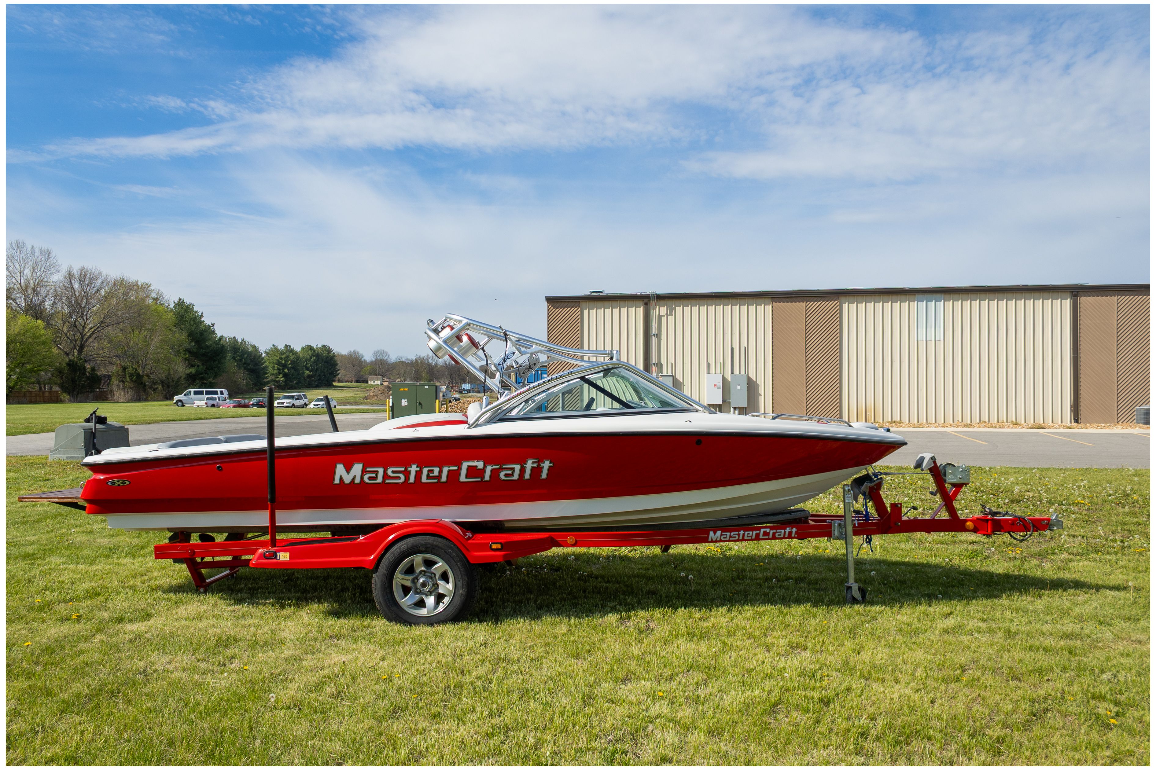 Red 2002 MasterCraft X-7 boat on trailer outdoors.