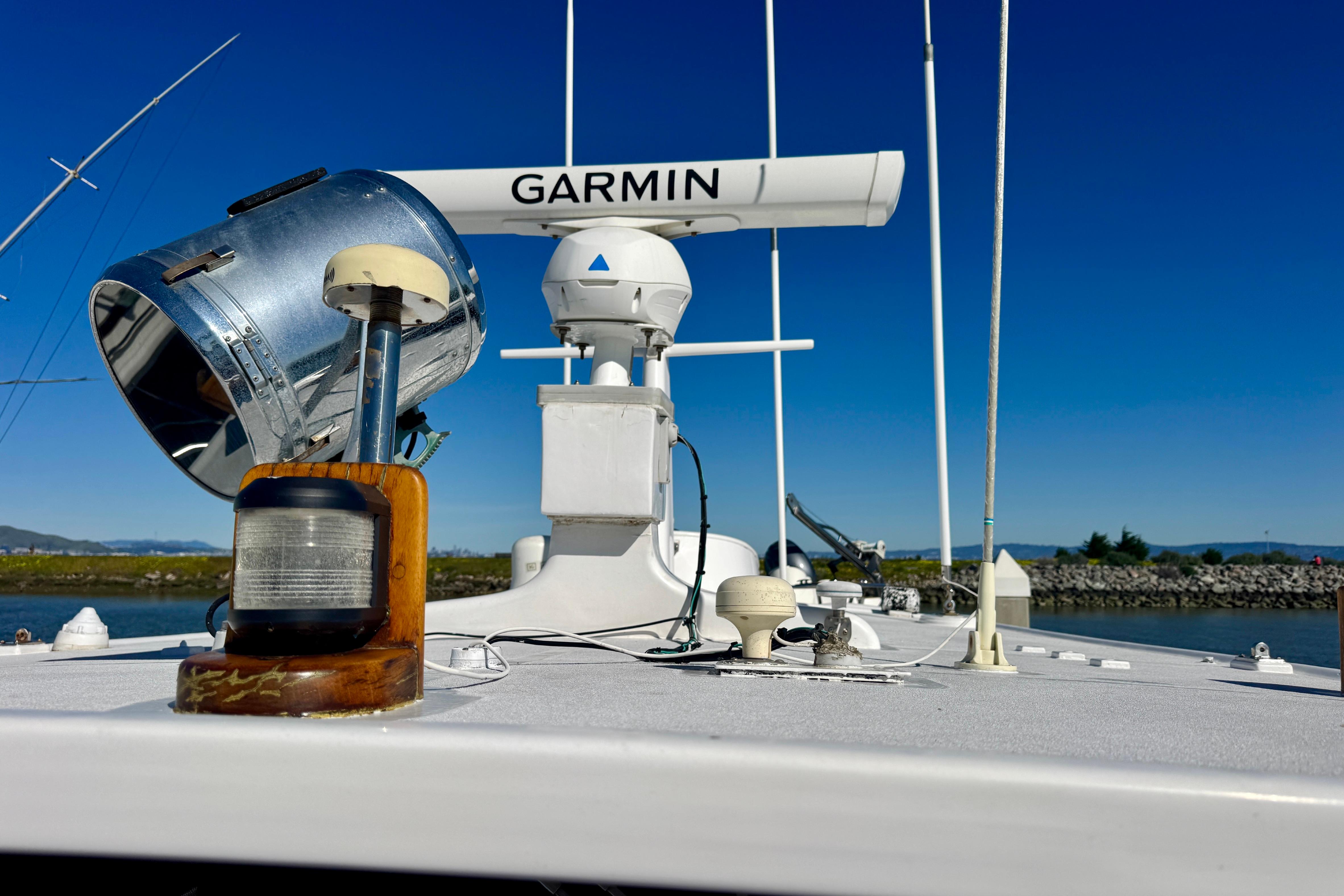 1958 Blanchard Pilothouse boat deck with Garmin radar and spotlight under clear blue sky.