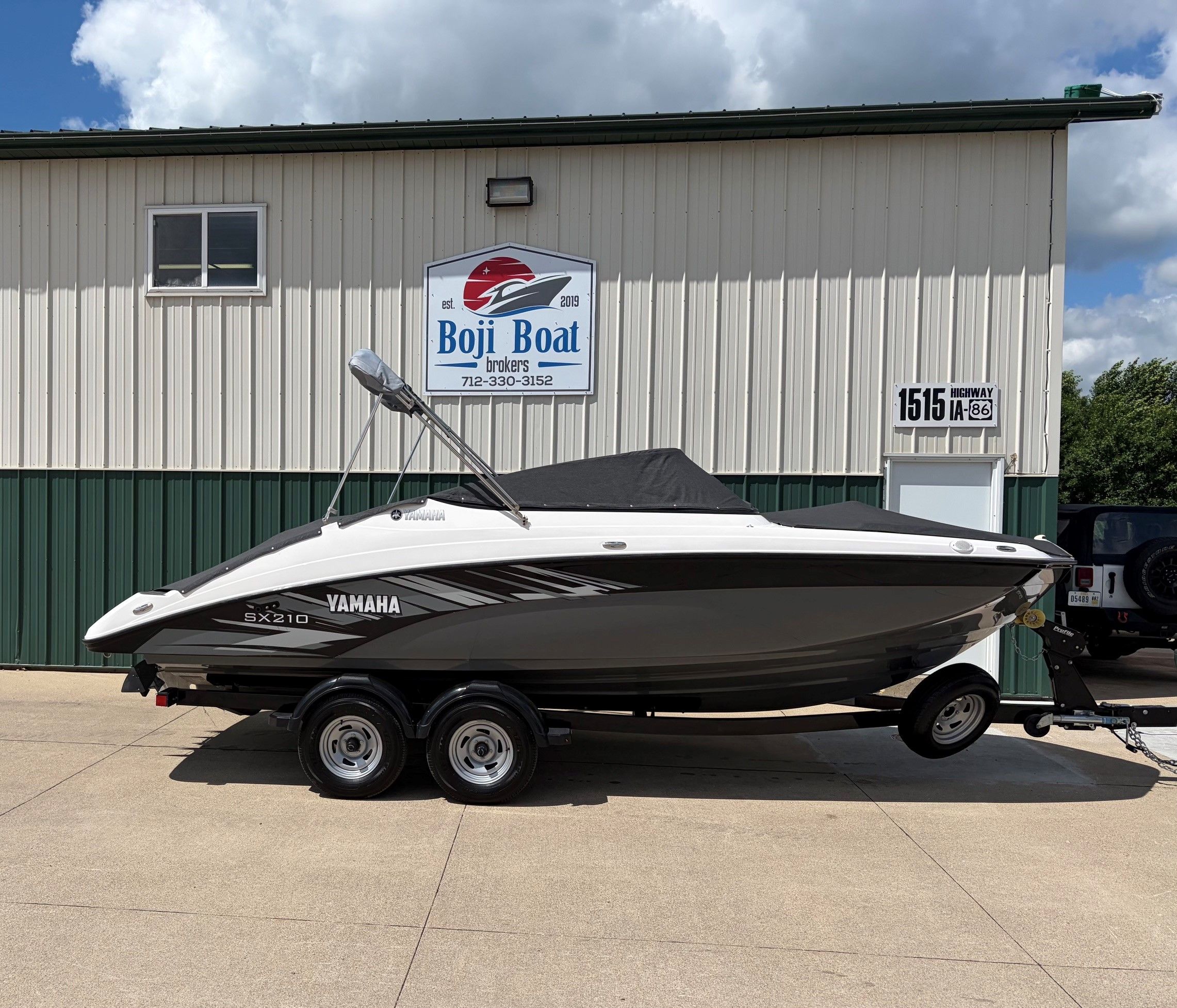 A Yamaha SX210 boat on a trailer in front of a building.
