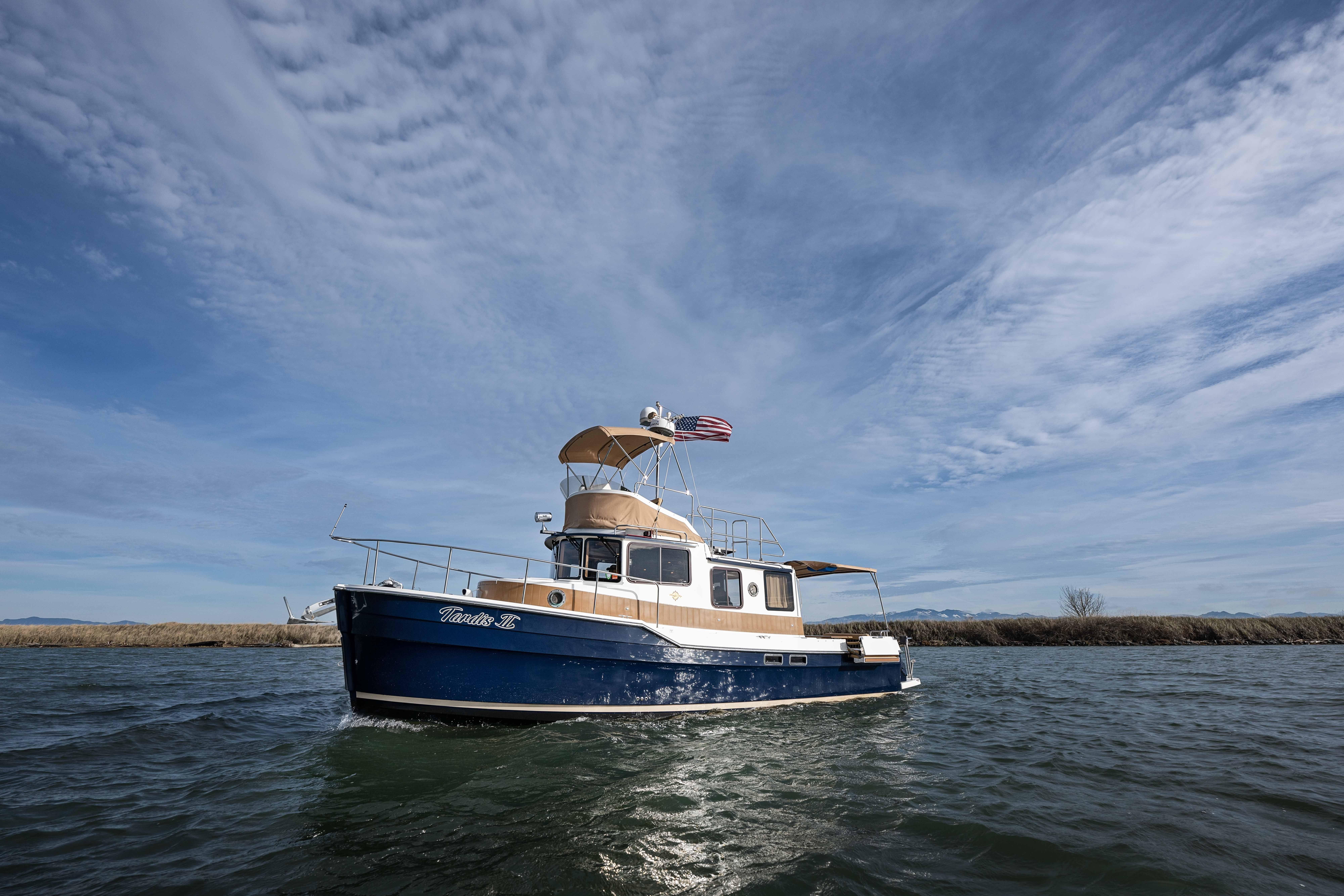 2014 Ranger Tug R-31 CB boat cruising on a calm waterway under a clear sky.