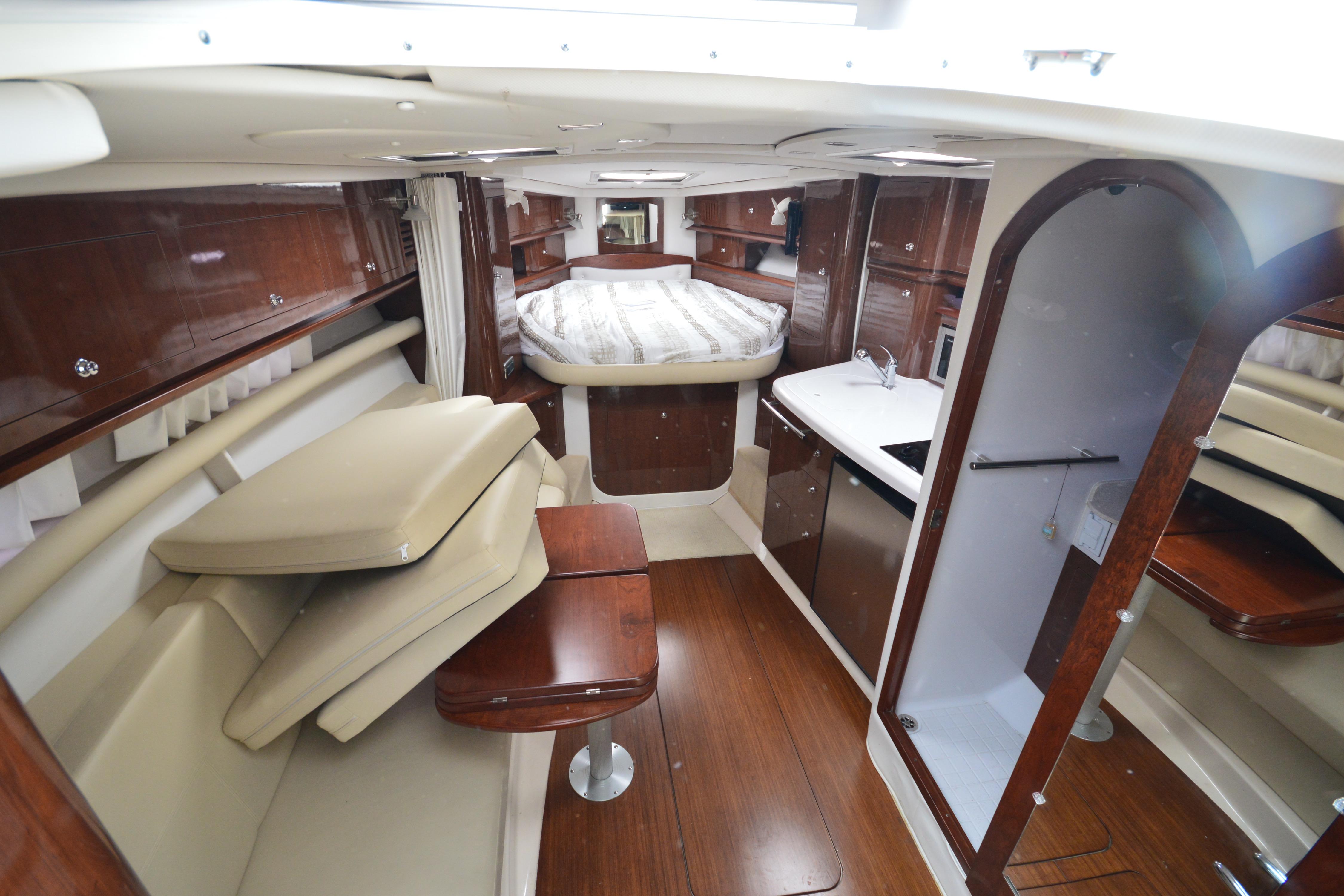 Luxurious interior of 2013 Four Winns V375 yacht with wood finishes and cozy seating.
