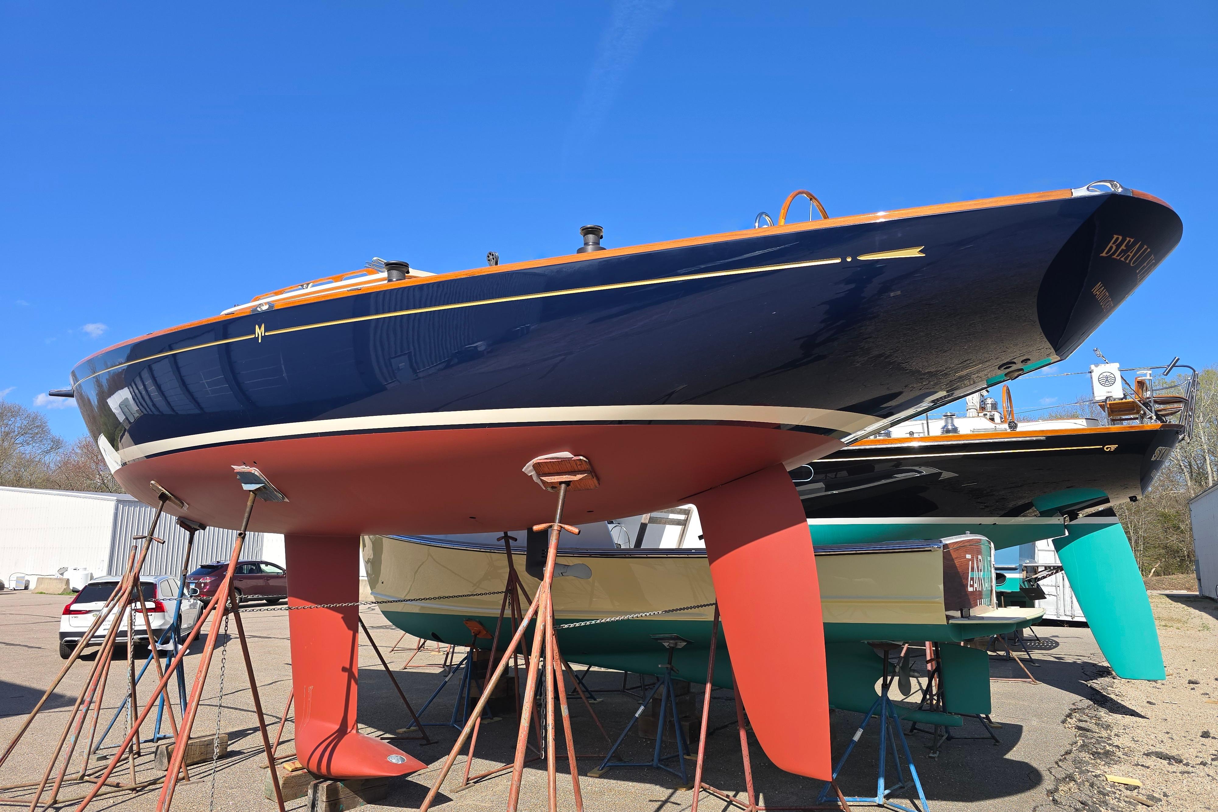 2016 Morris M36x sailboat on stands, blue hull, red keel, clear sky background.
