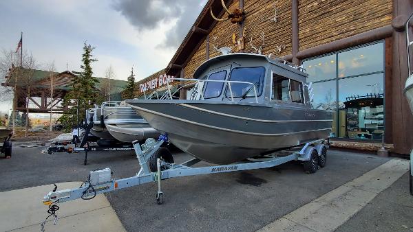 2023 Spartan 220 Maximus boat on trailer outside a wooden building.
