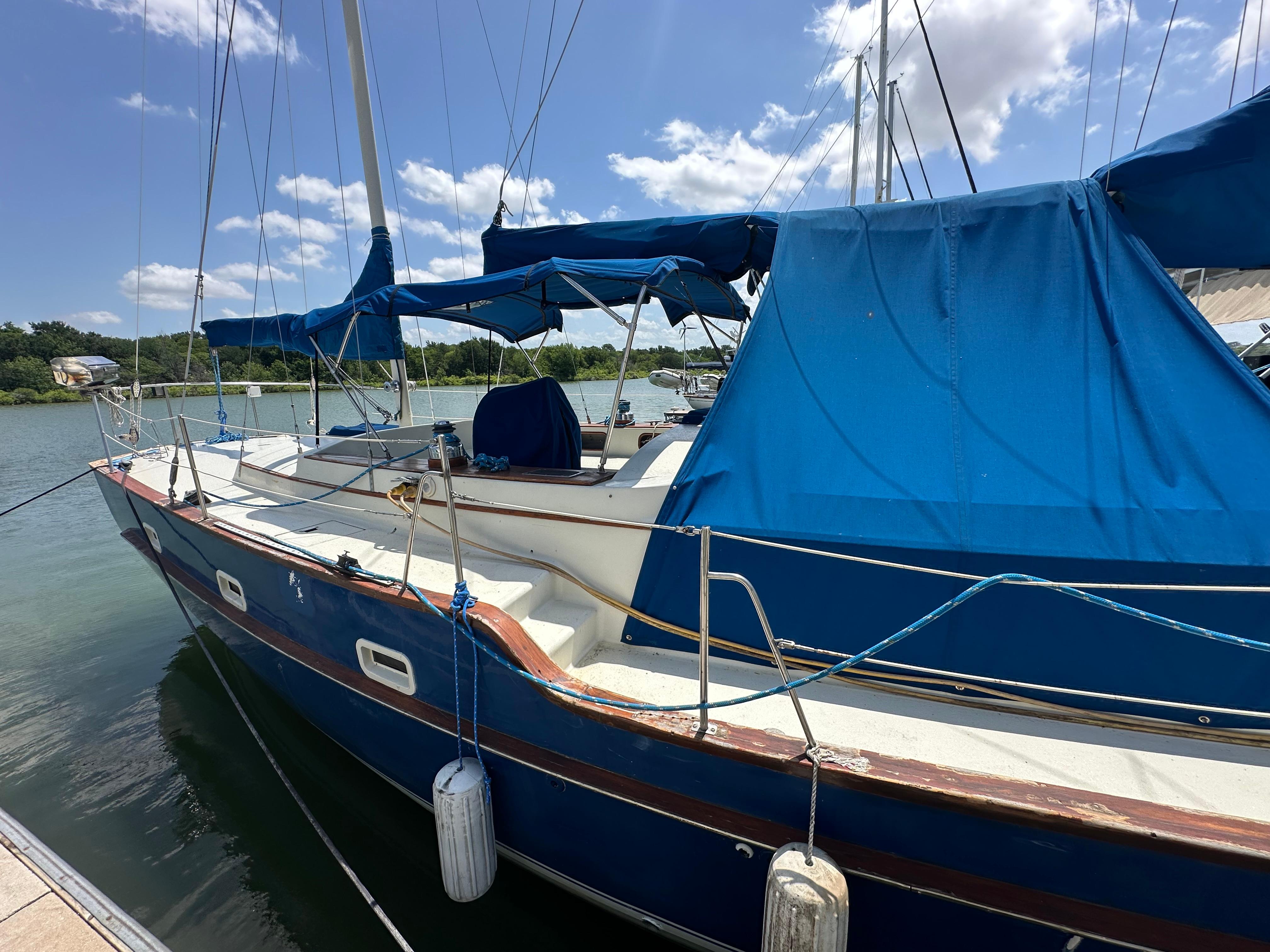 1982 Irwin 46 sailboat docked, featuring blue canvas covers and clear skies.