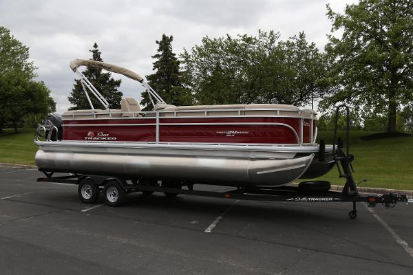 2024 Sun Tracker Party Barge 24 DLX pontoon boat on trailer in parking lot.